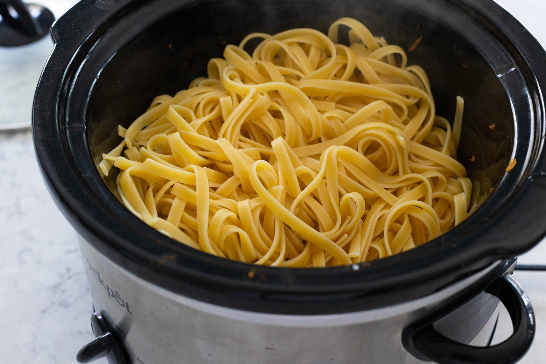 The boiled pasta has been added to the slowcooker.