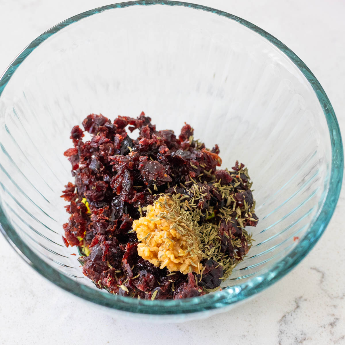 The chopped cranberries and minced garlic are in a mixing bowl.
