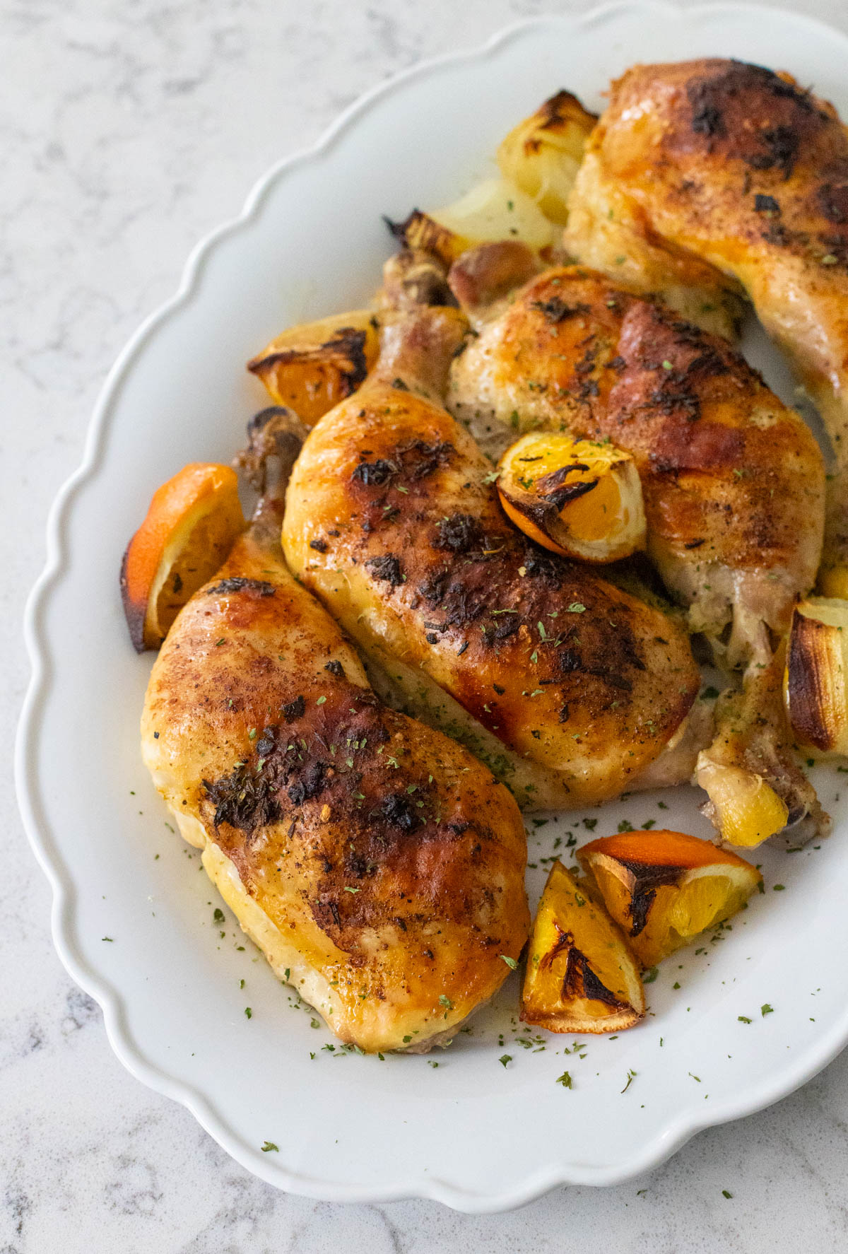 The roasted chicken pieces are on a white platter ready to be served at the table.