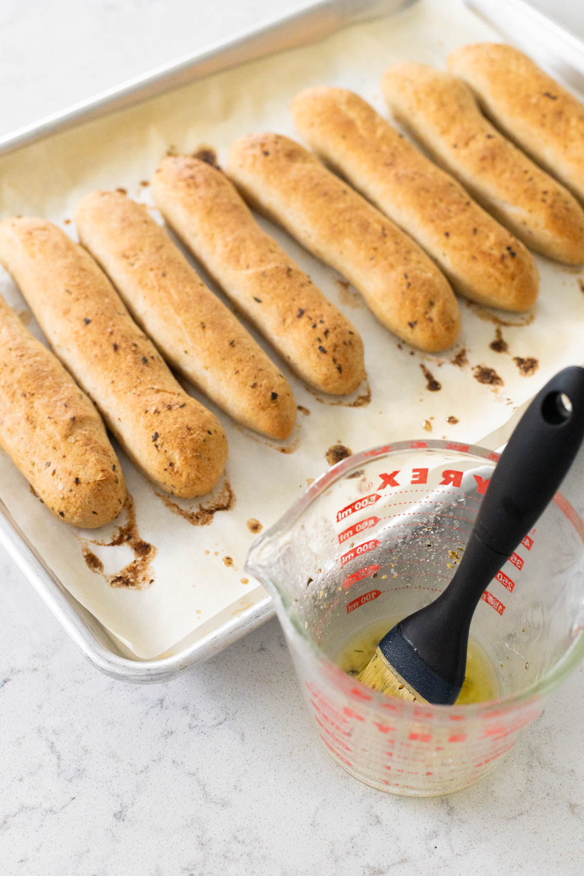 The baked breadsticks on the pan are waiting for the second brushing of melted butter.