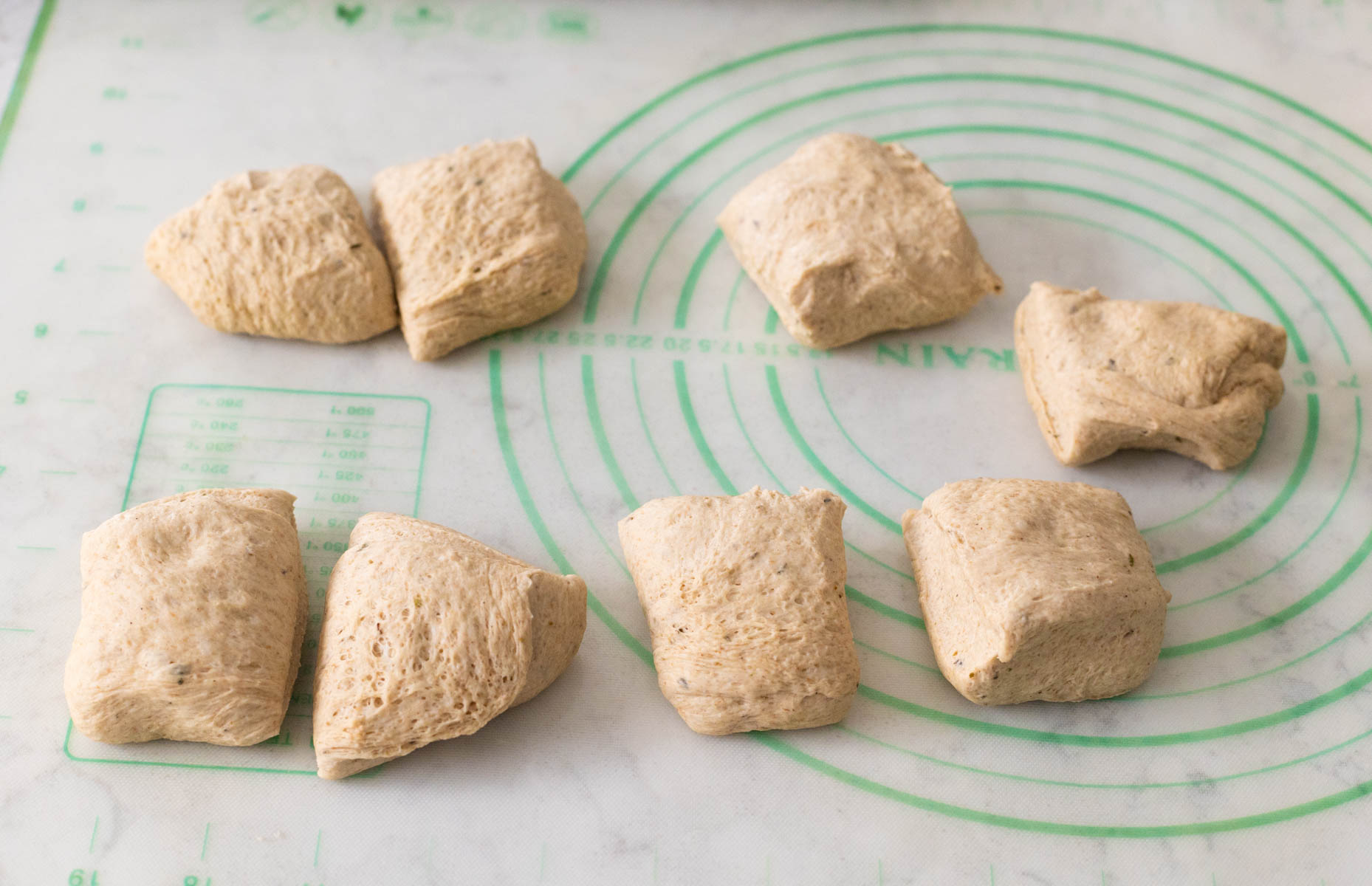 The 8 pieces of dough on a baking mat.