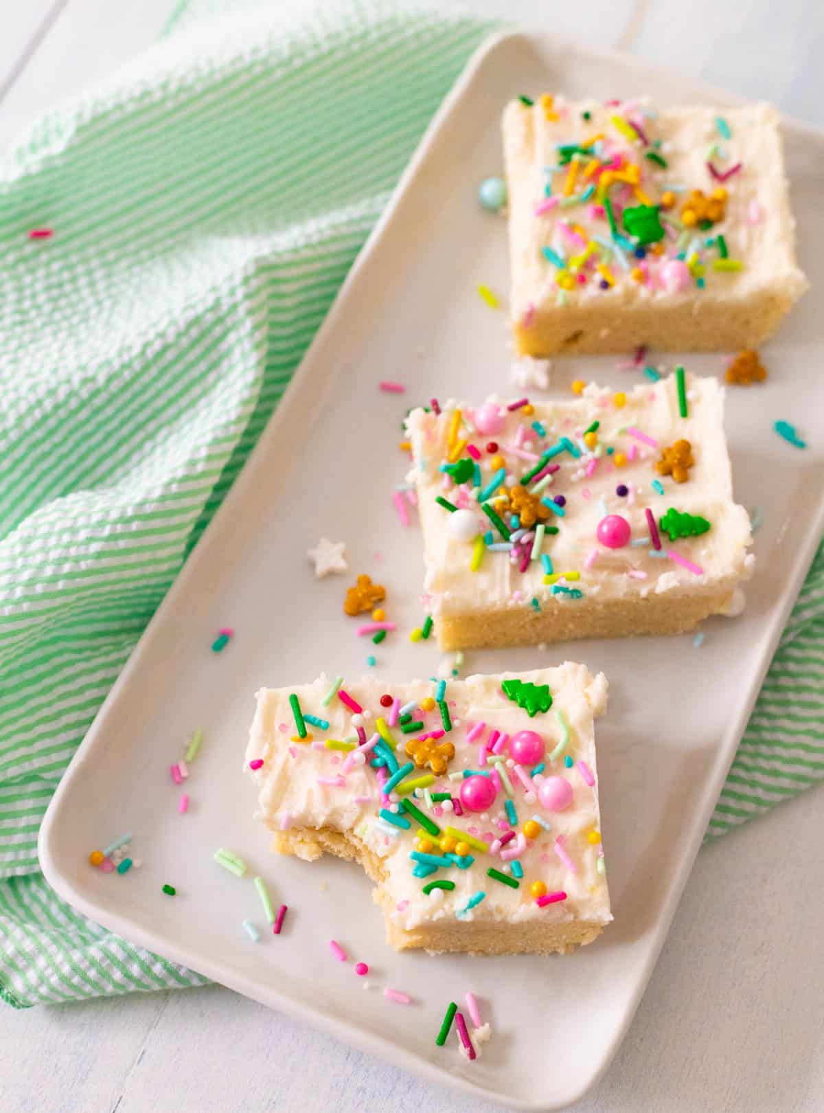 The platter of sugar cookie bars has a green napkin draped on the side.