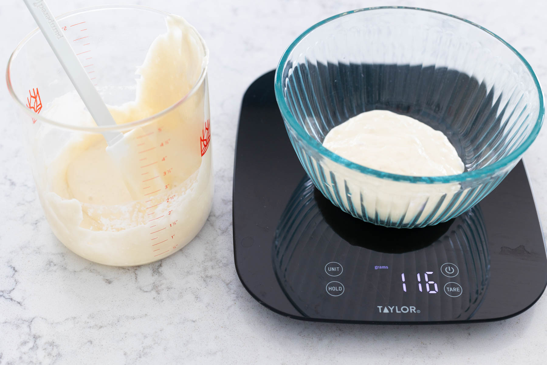 A portion of sourdough starter has been scraped into the empty mixing bowl on the food scale.