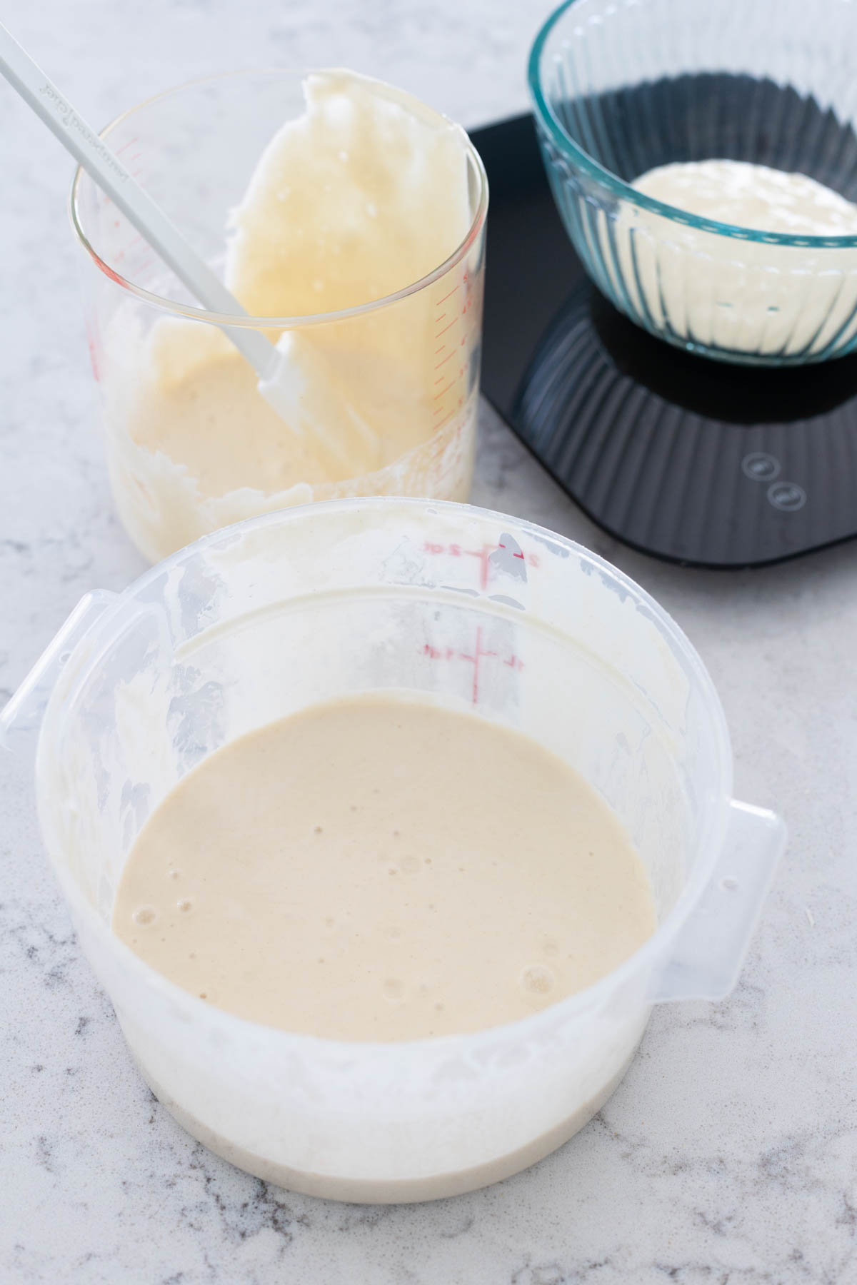 The plastic tub of sourdough starter discard sits in front of the weighing station.