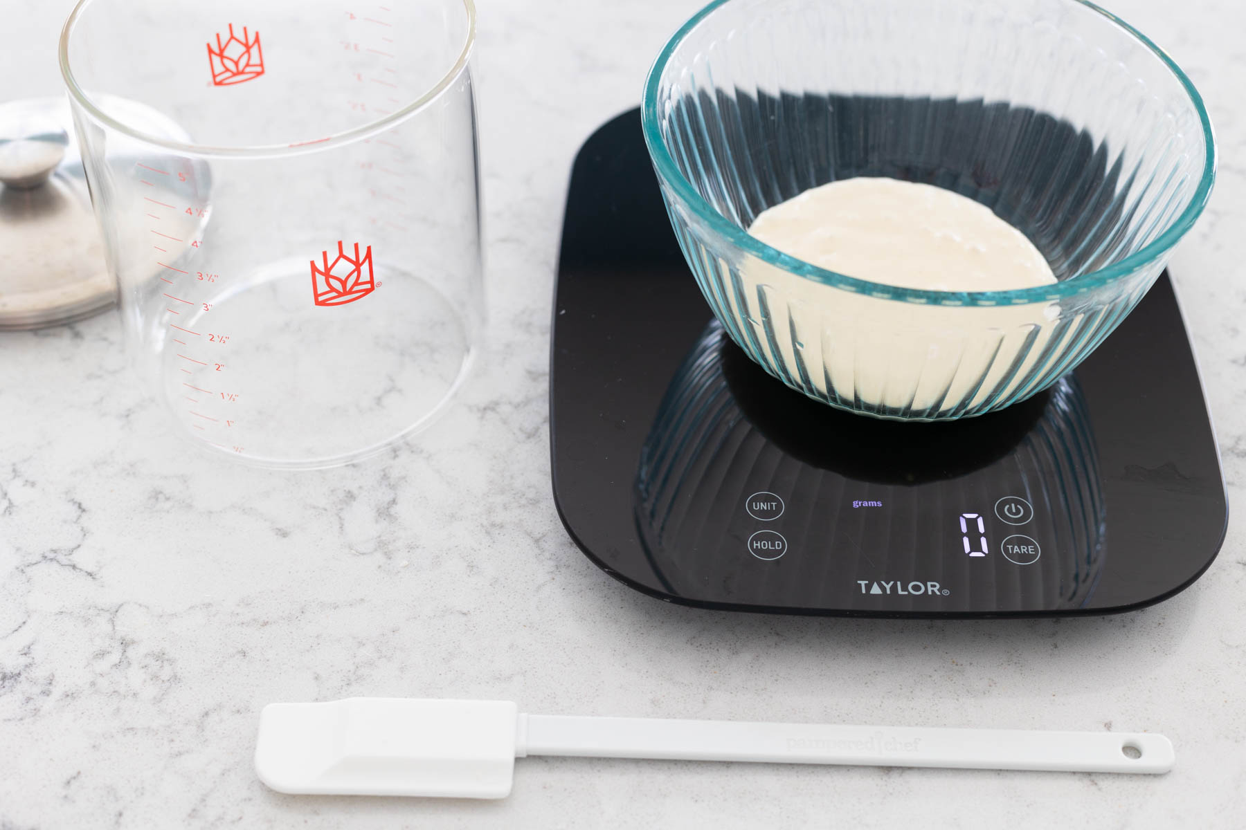 The food scale has the measuring bowl with sourdough starter in it but has been set to read 0 grams.