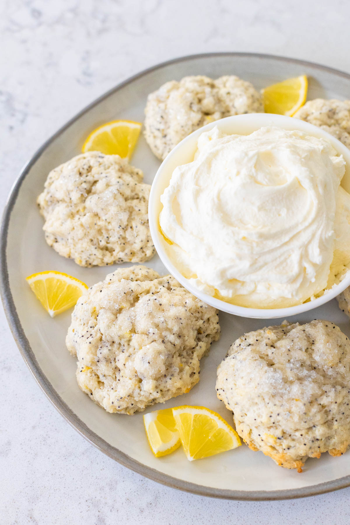 The platter of scones has a bowl of mock clotted cream in the center.