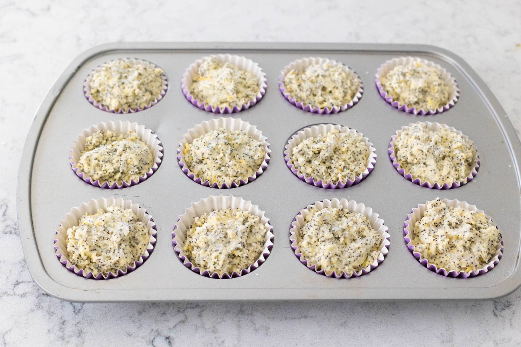 The lemon muffins have been spooned into a muffin tin.