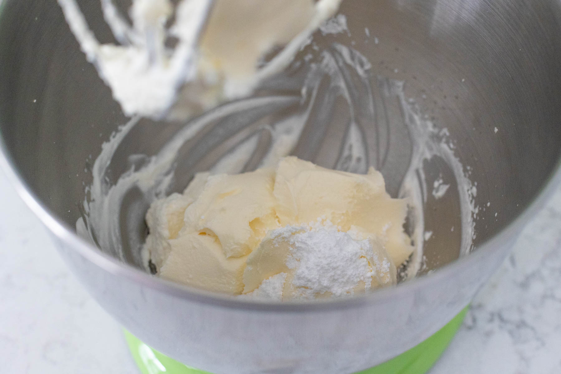 The mascarpone cheese and powdered sugar have been added to the mixing bowl.