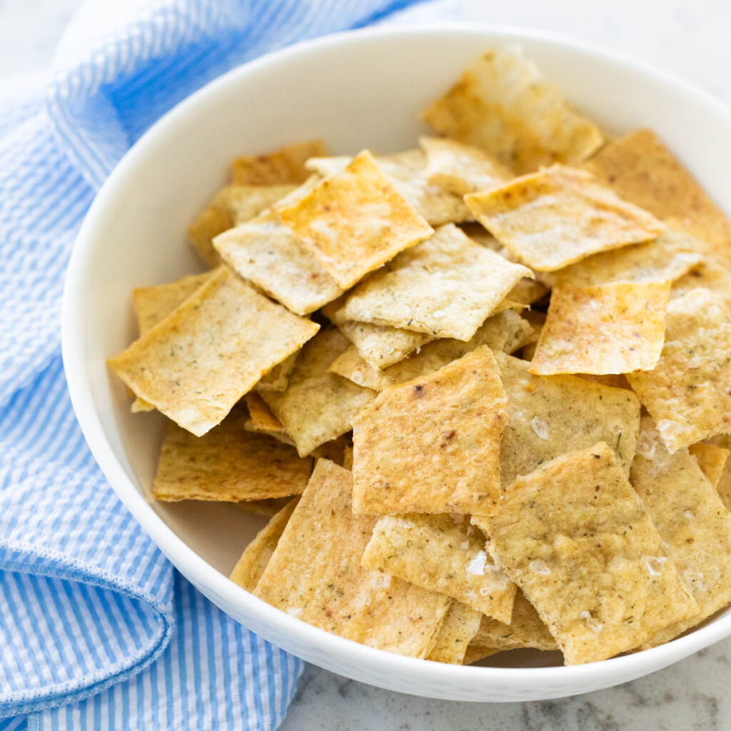A white bowl is filled with homemade sourdough starter crackers.