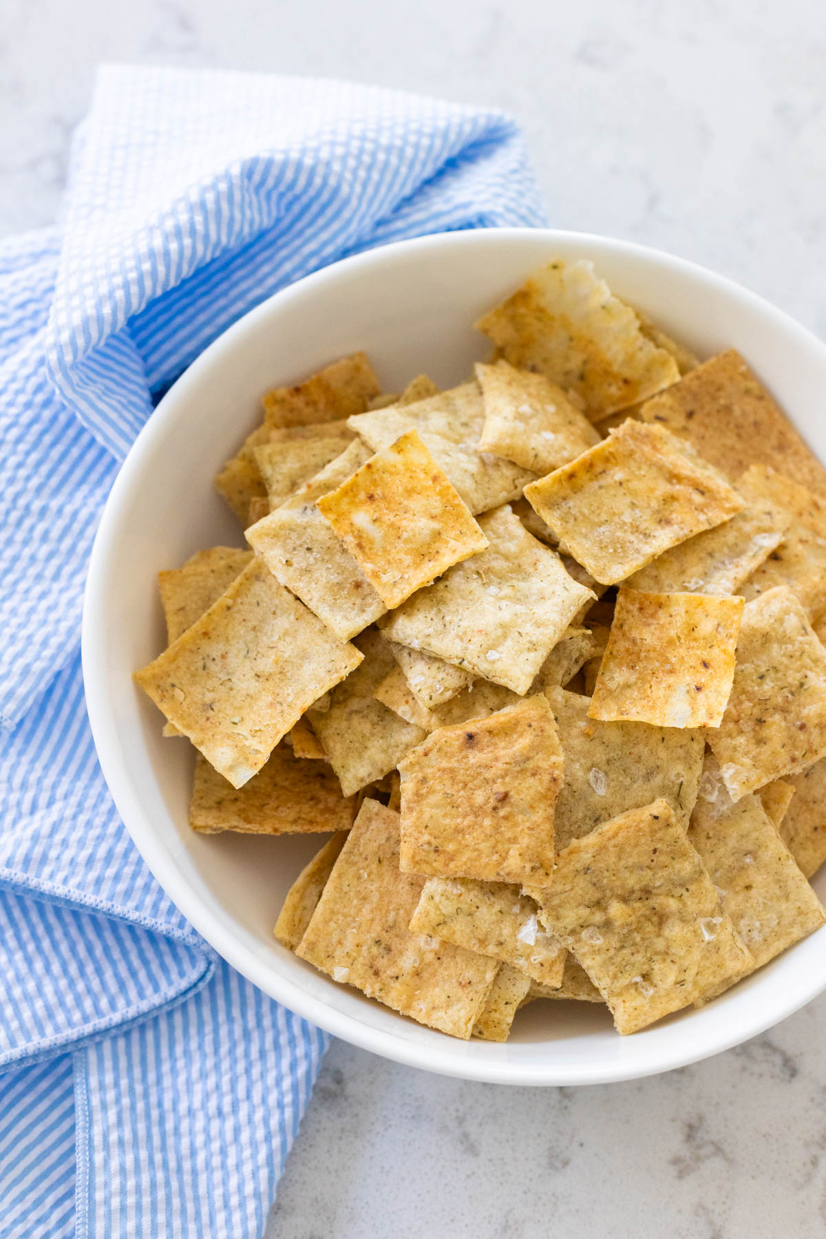 A white bowl is filled with homemade sourdough starter crackers.