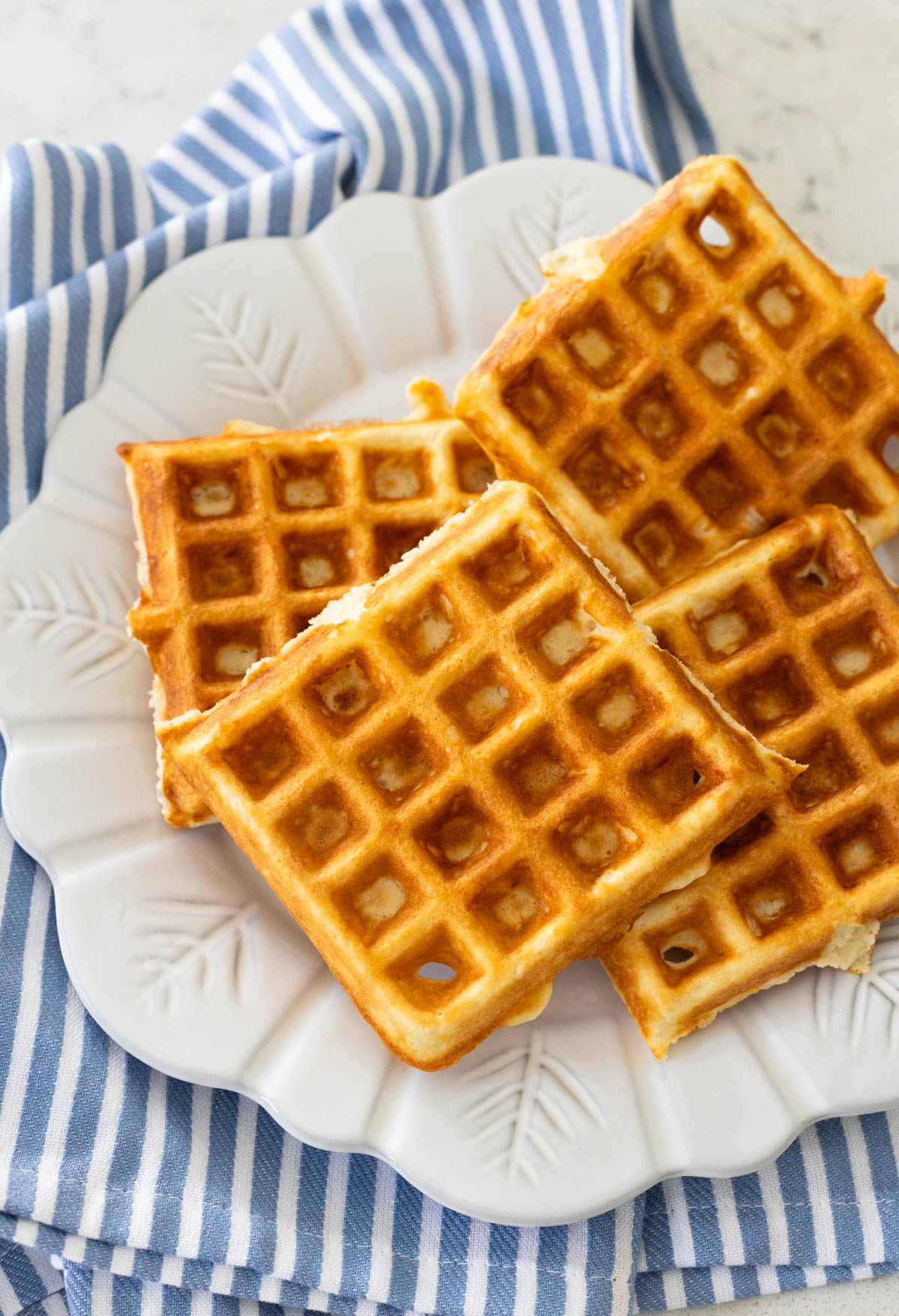 The waffles are served on a white plate resting on a blue and white striped napkin.
