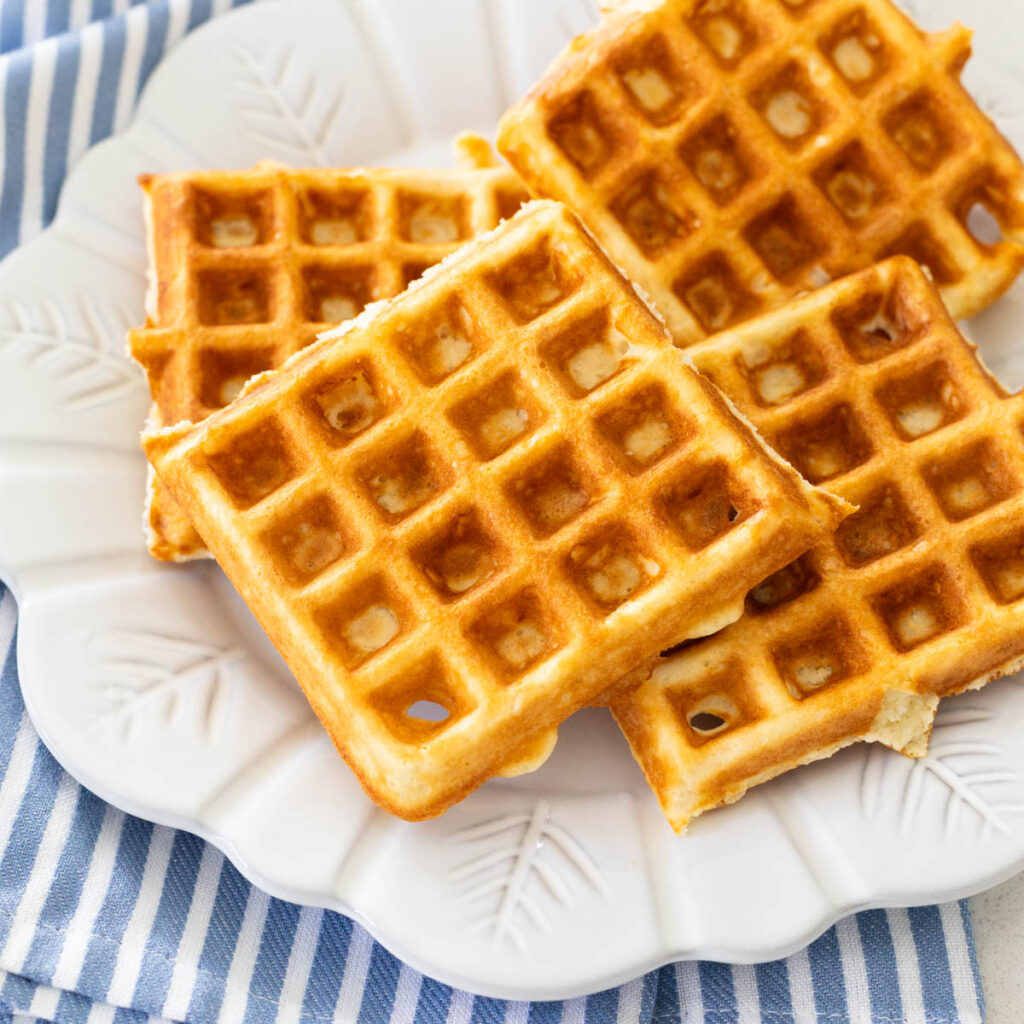 The waffles are served on a white plate resting on a blue and white striped napkin.