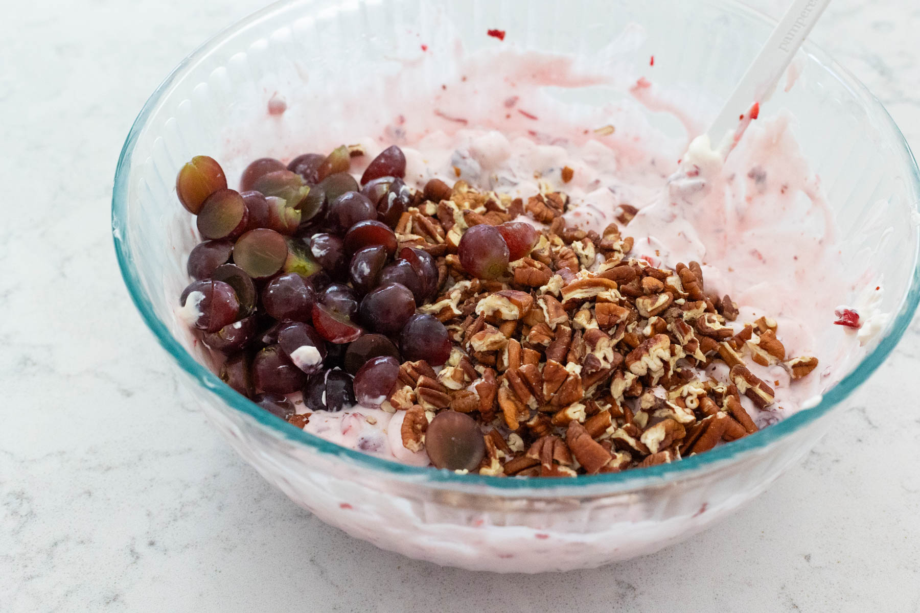 The chopped grapes and pecans have been added to the dish.
