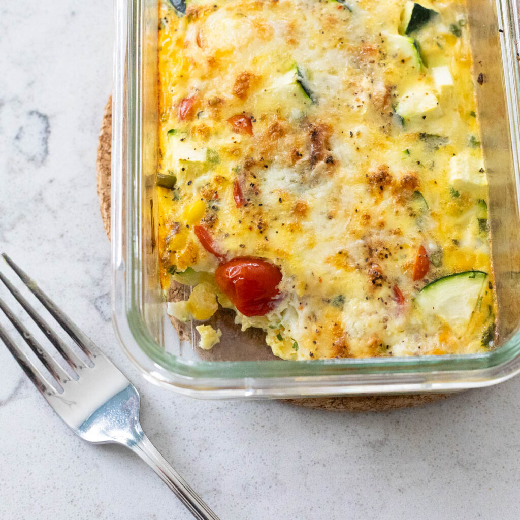 A baked egg and veggie mixture is in an individual serving container.