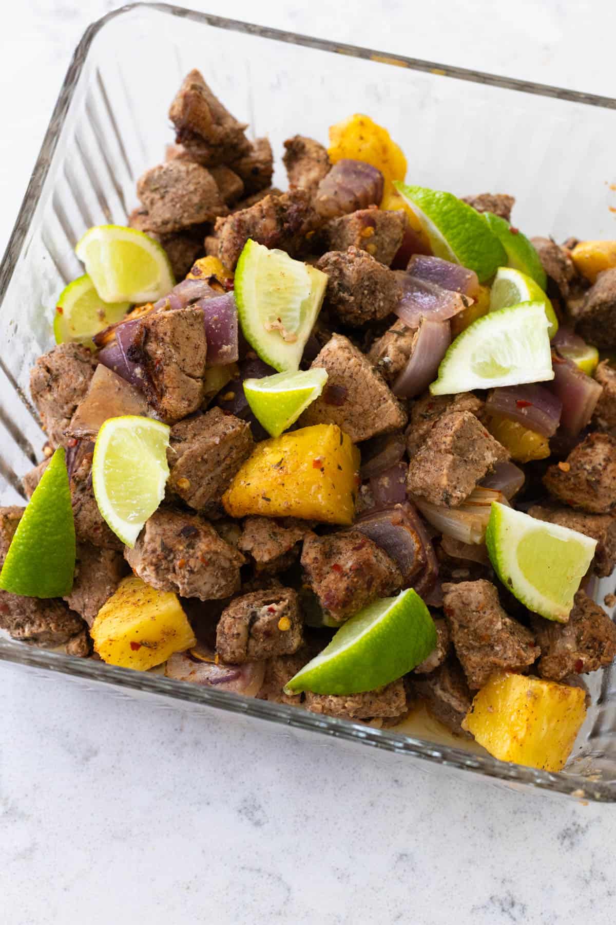 The cooked jerk pork and pineapple are in a serving container ready for the table.