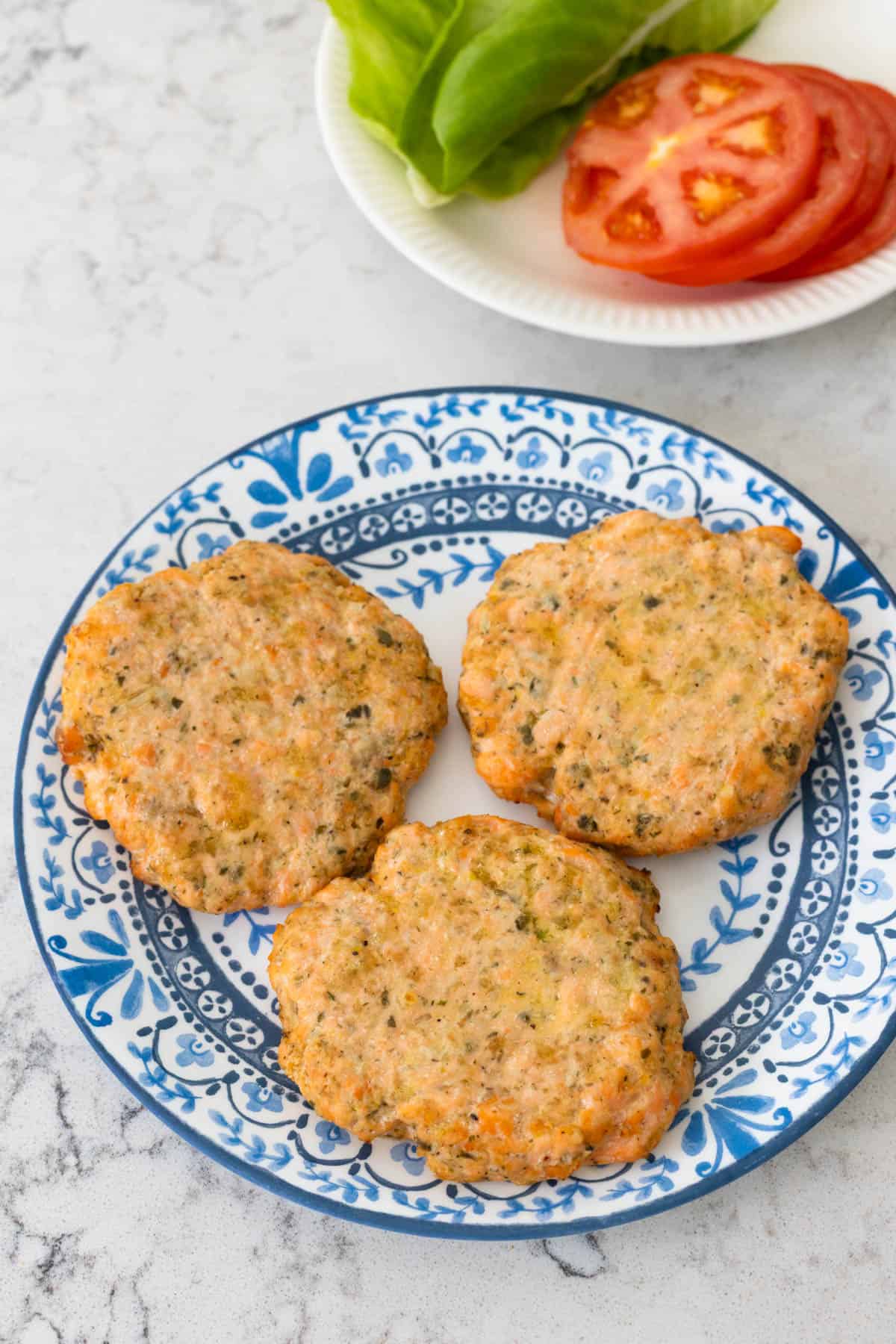 The cooked burgers are on a blue and white plate.