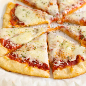 A plain cheese pizza with tomato sauce has been baked with a sourdough discard crust that is now golden brown.
