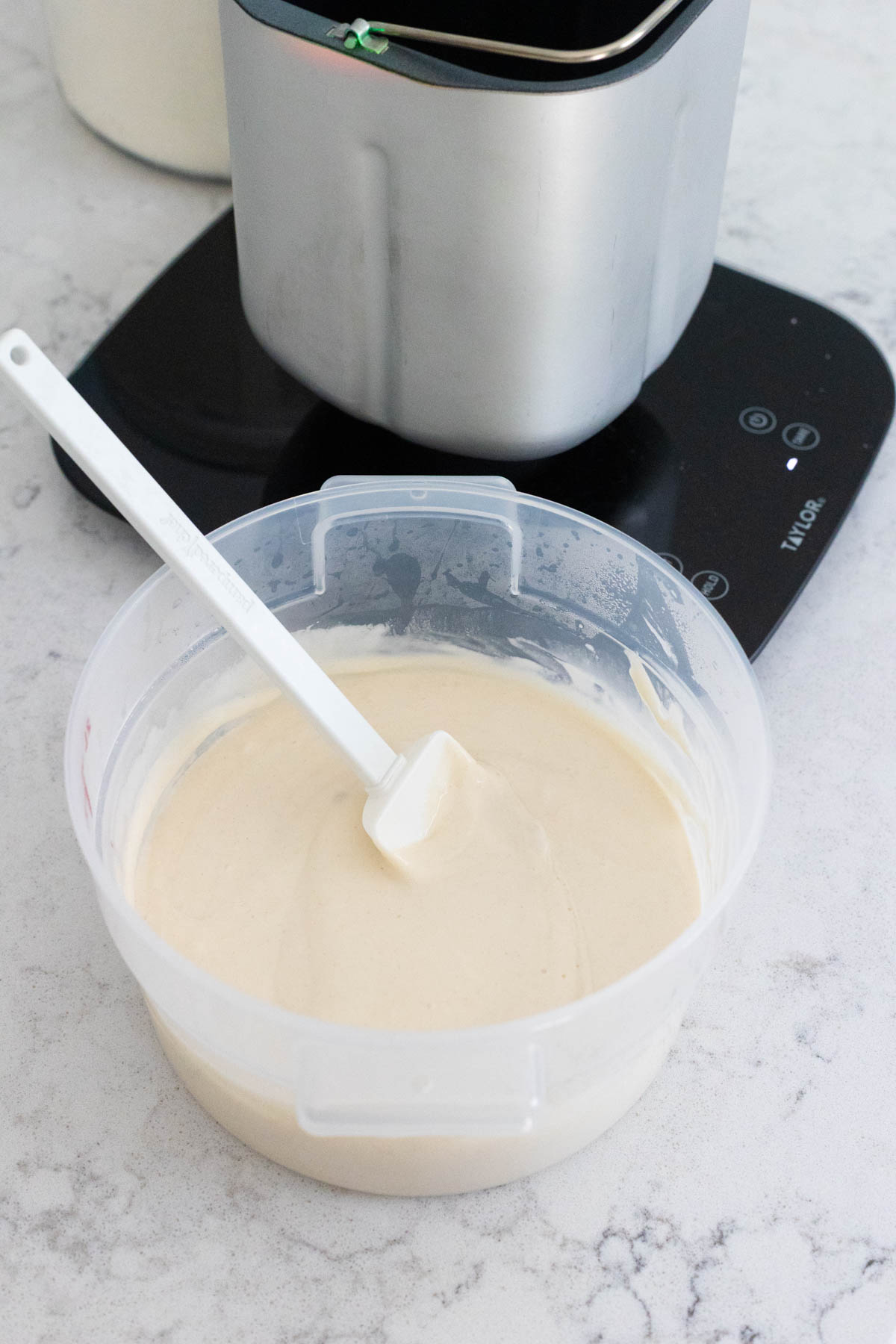 A big tub of sourdough starter discard is next to the food scale.