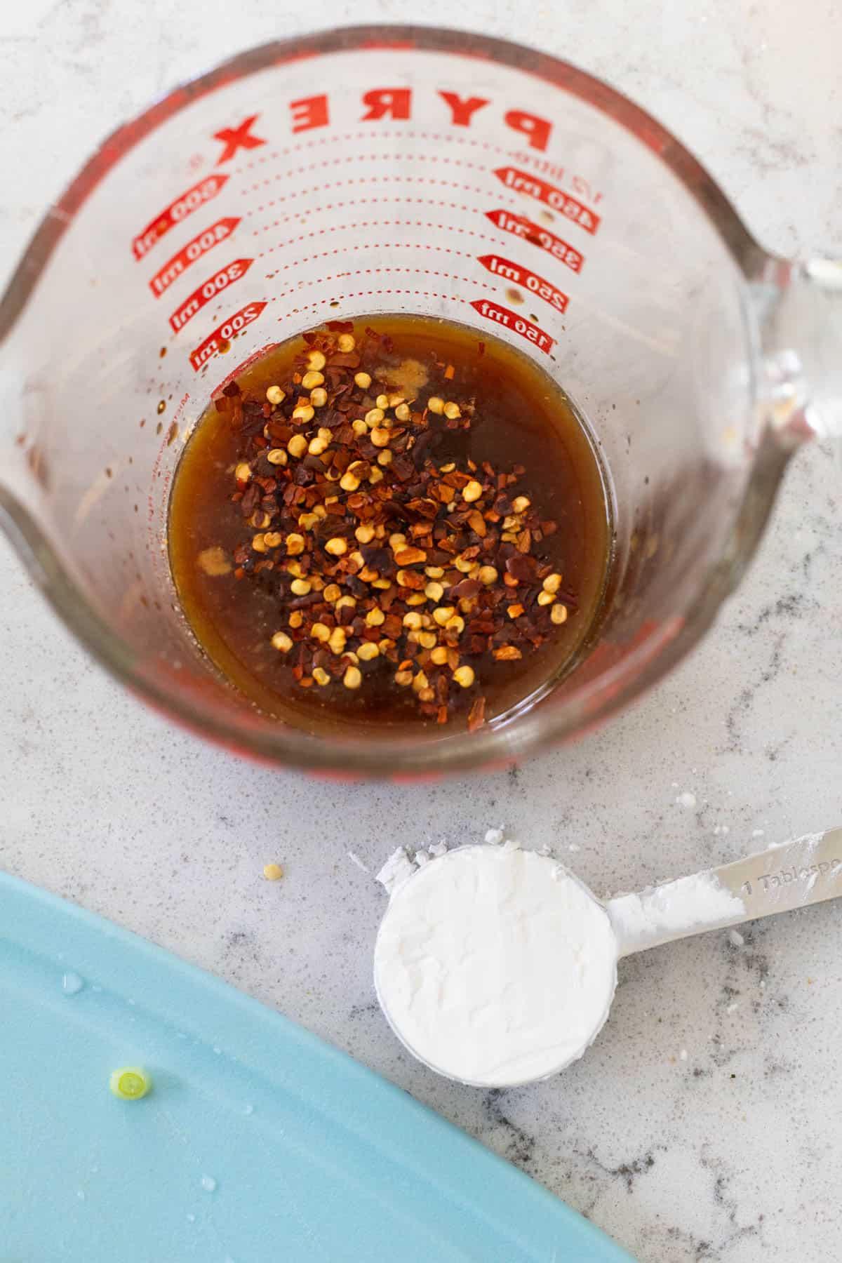 The easy stir fry sauce has been measured into a glass measuring cup. A tablespoon of corn starch rests nearby.