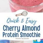 A red cherry almond smoothie in a cup with a striped straw has almonds scattered on the counter next to it.