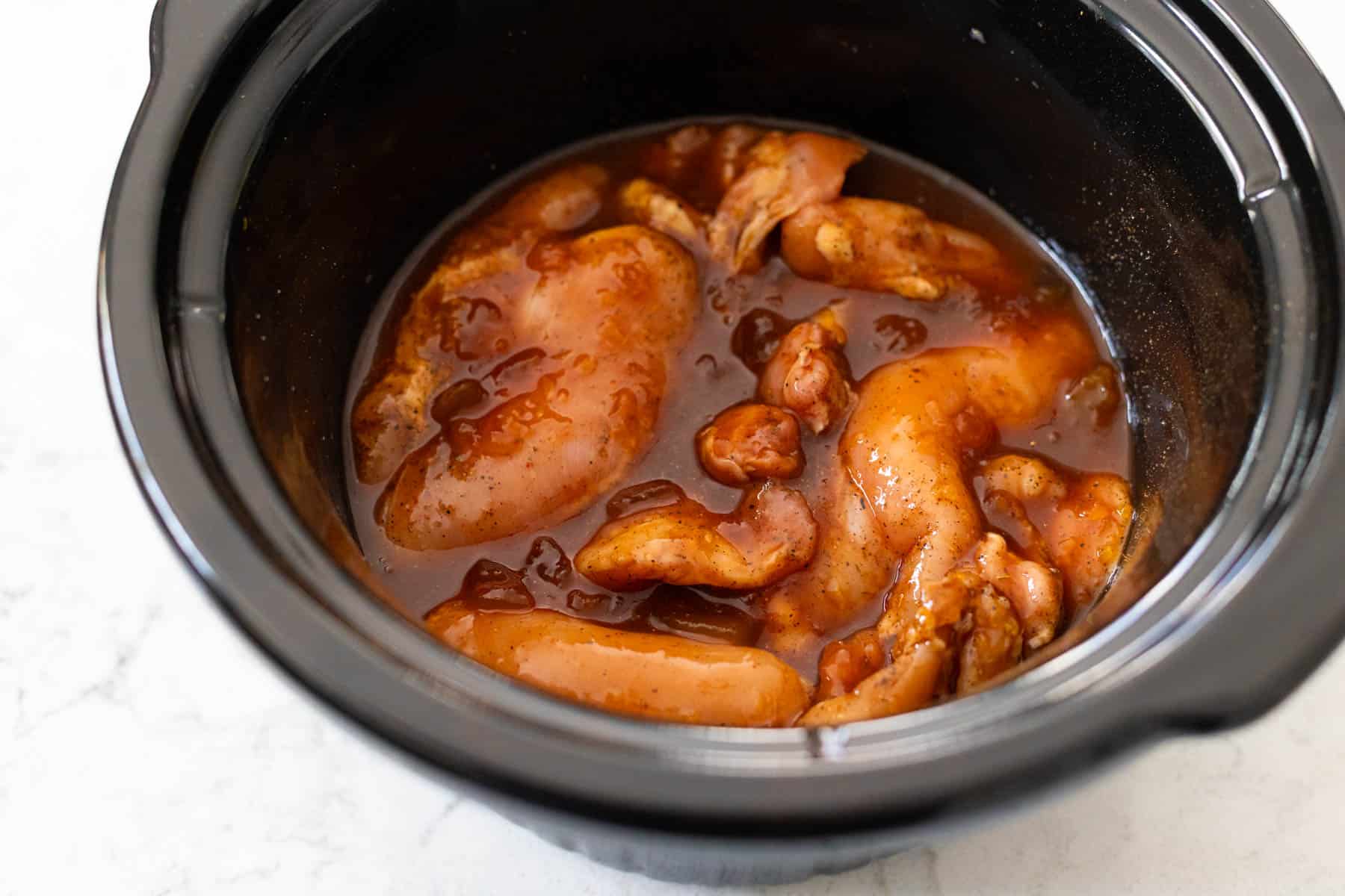 The raw chicken is coated in the peach glaze and is ready to be cooked.