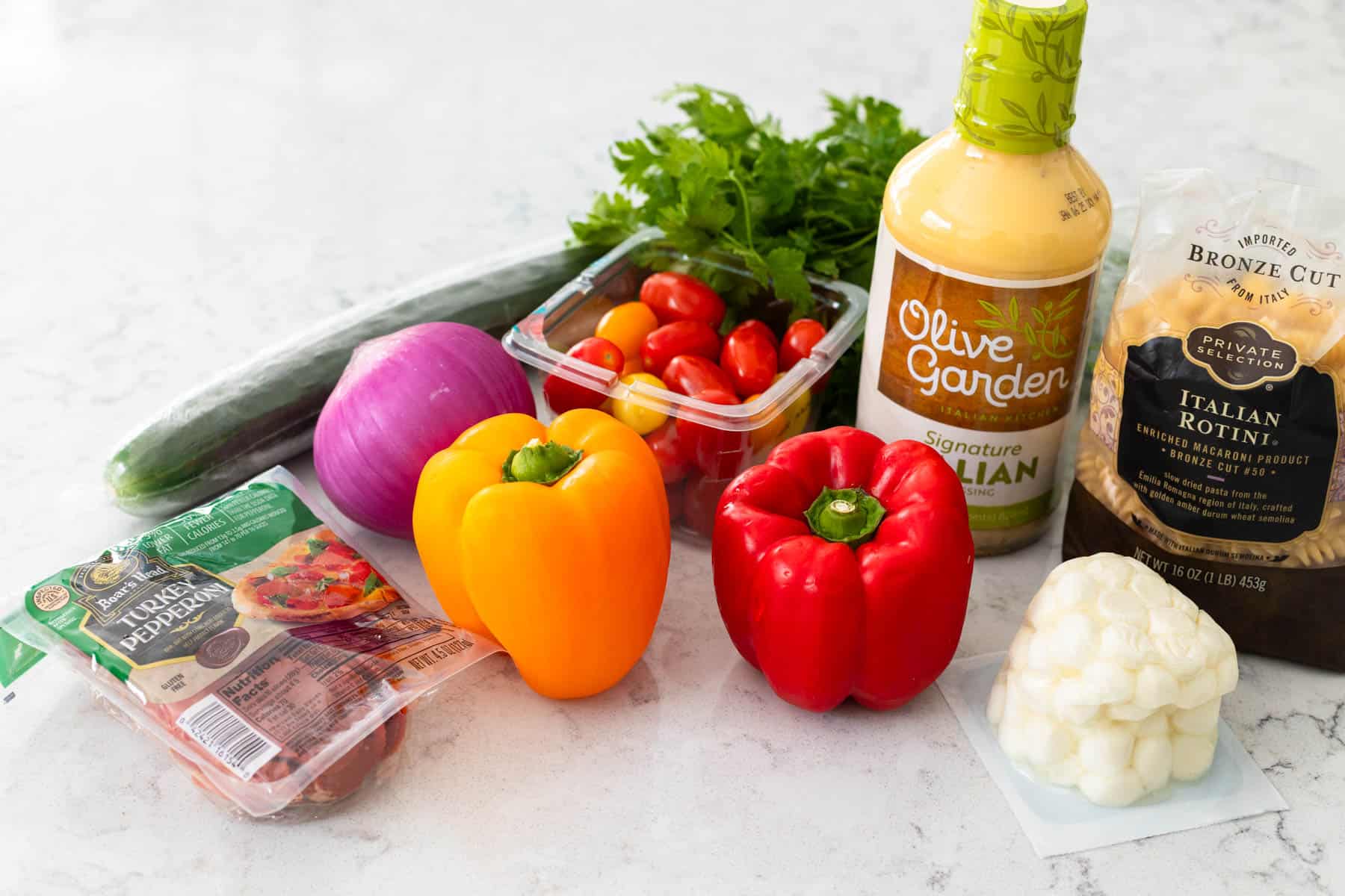 The ingredients to make the pasta salad are on the counter.