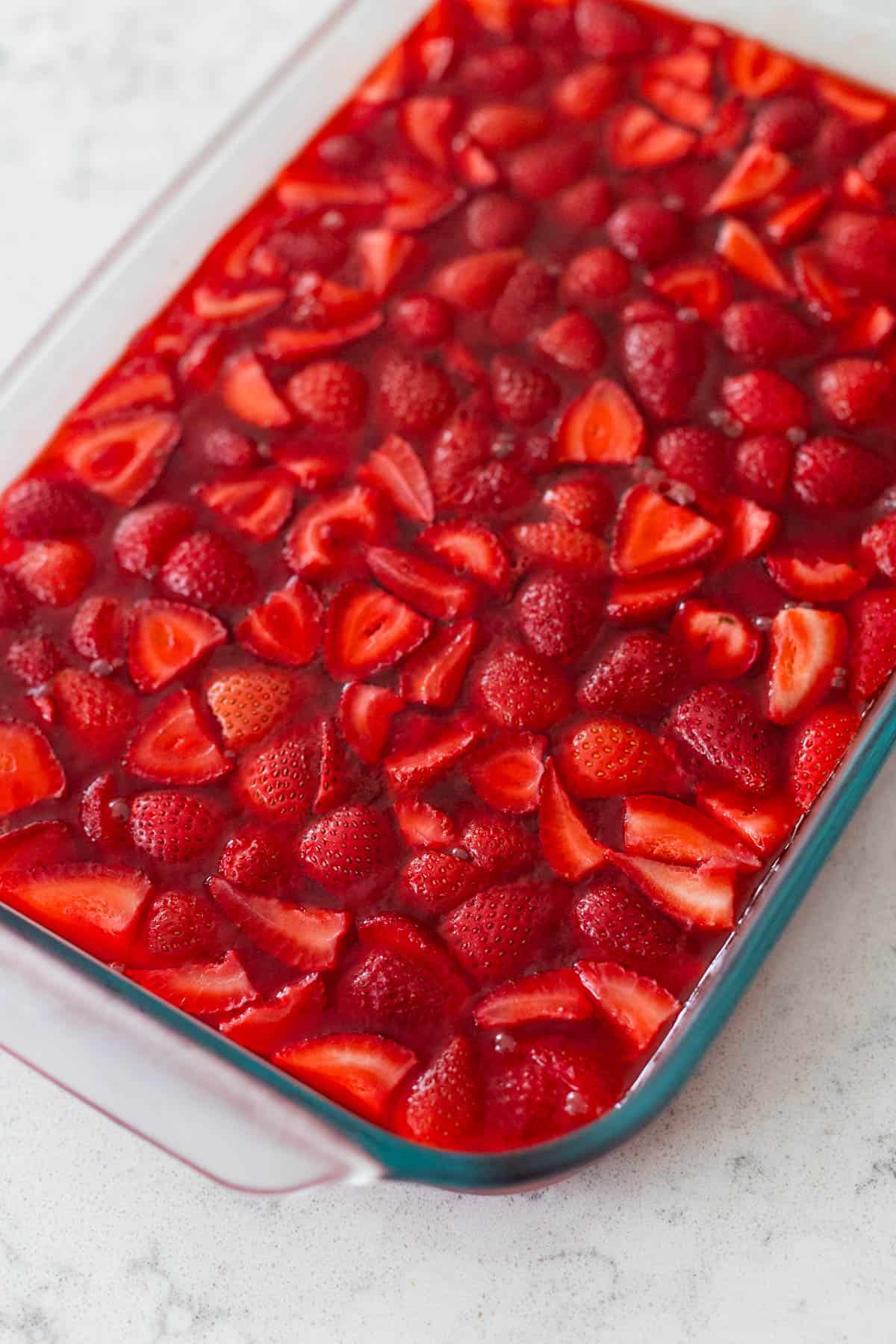 Un plat de Jell-O aux fraises avec des fraises mélangées est sur le comptoir de la cuisine.
