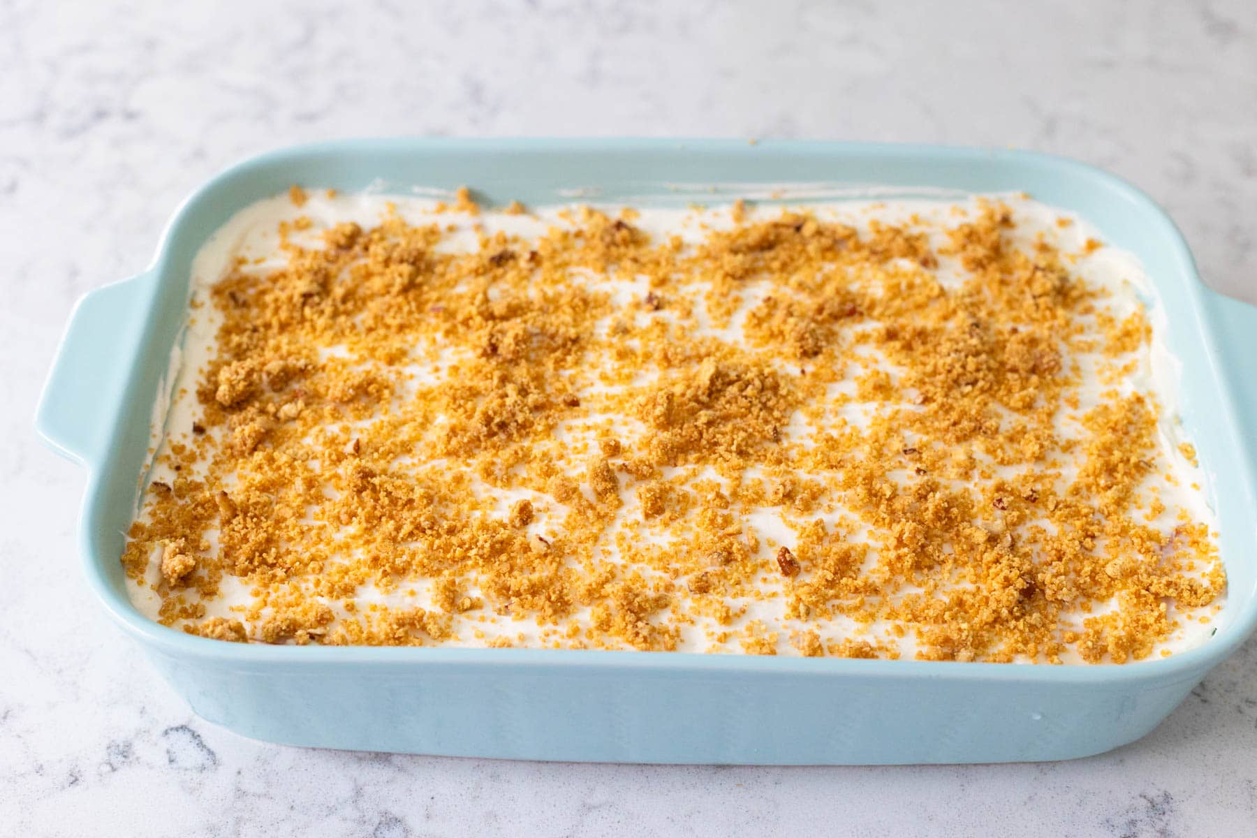 The finished peach dessert has the reserved graham cracker crumble sprinkled over the top.