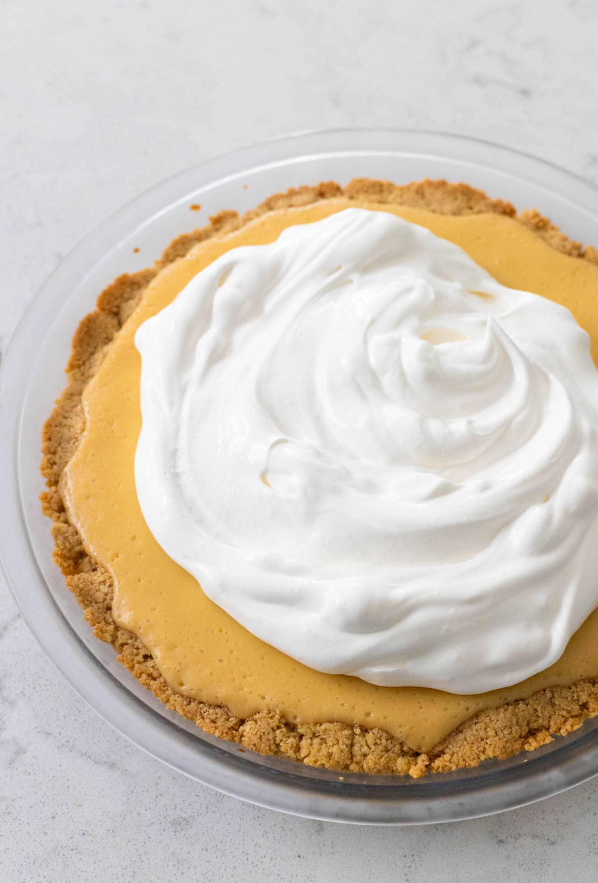 Homemade whipped cream has been spooned onto the lemon pie.