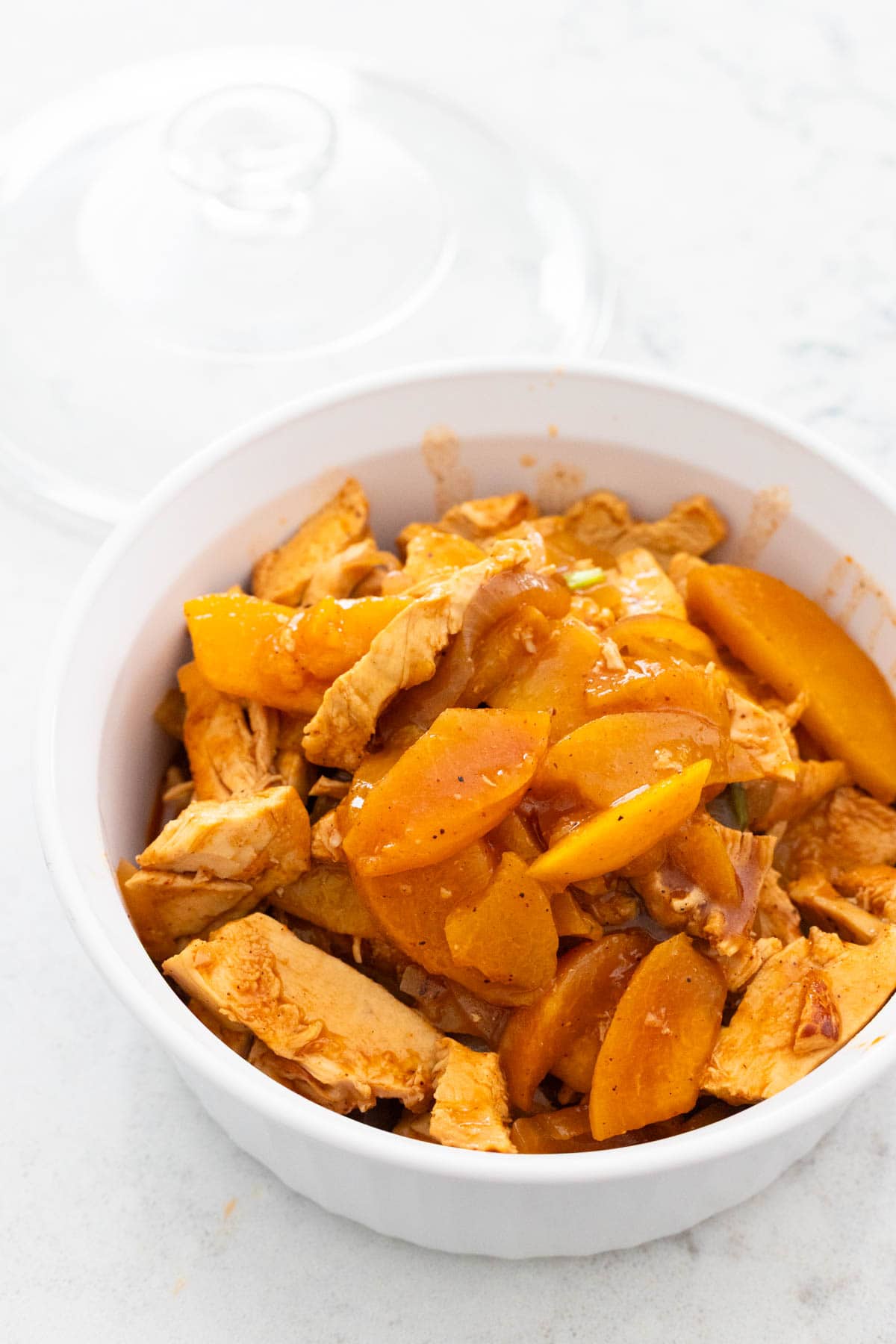 The cooked chicken and peach taco filling is in a storage container ready for the fridge.