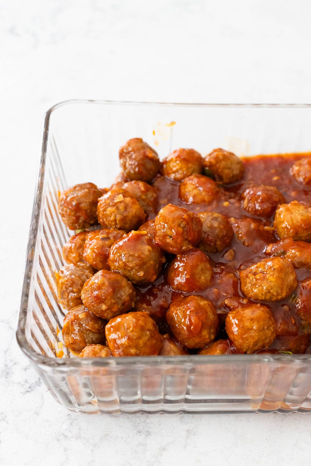 The storage dish is filled with the cooked meatballs and sauce.