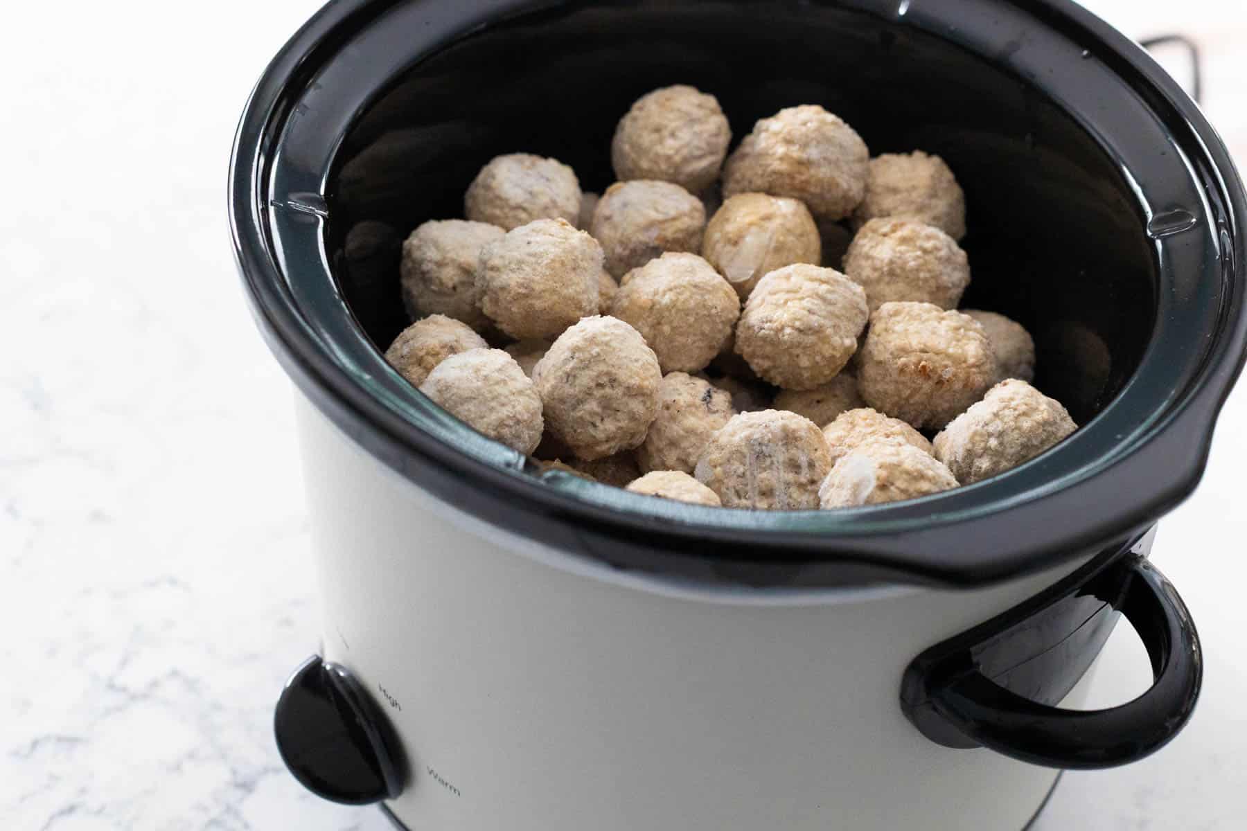 The frozen meatballs are sitting in the crockpot before any sauce is added.