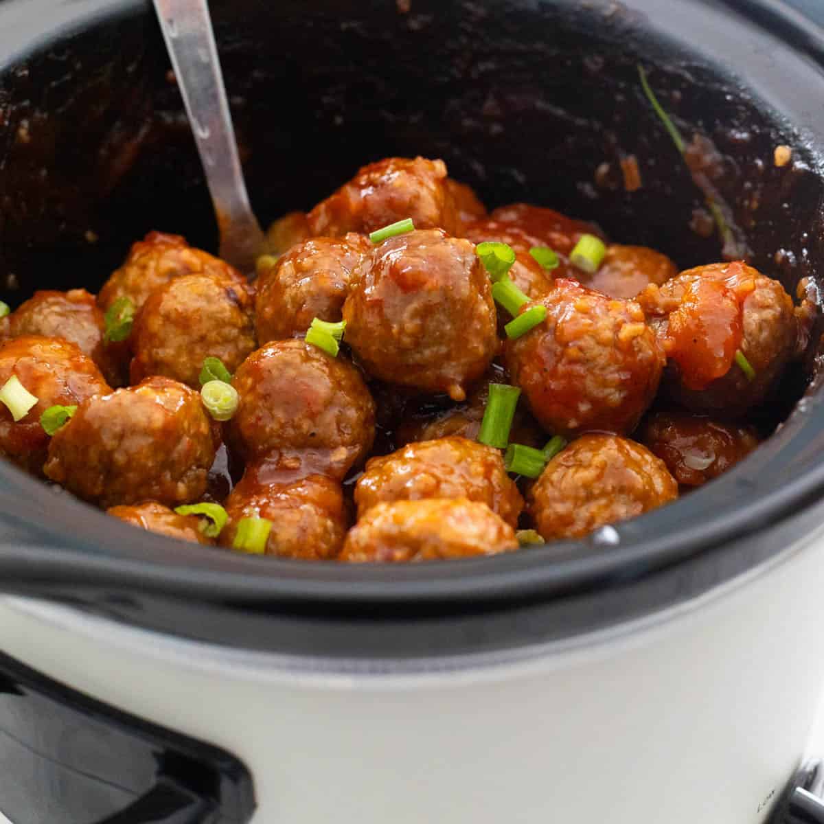 The finished meatballs are in the crockpot with a serving spoon ready to serve.