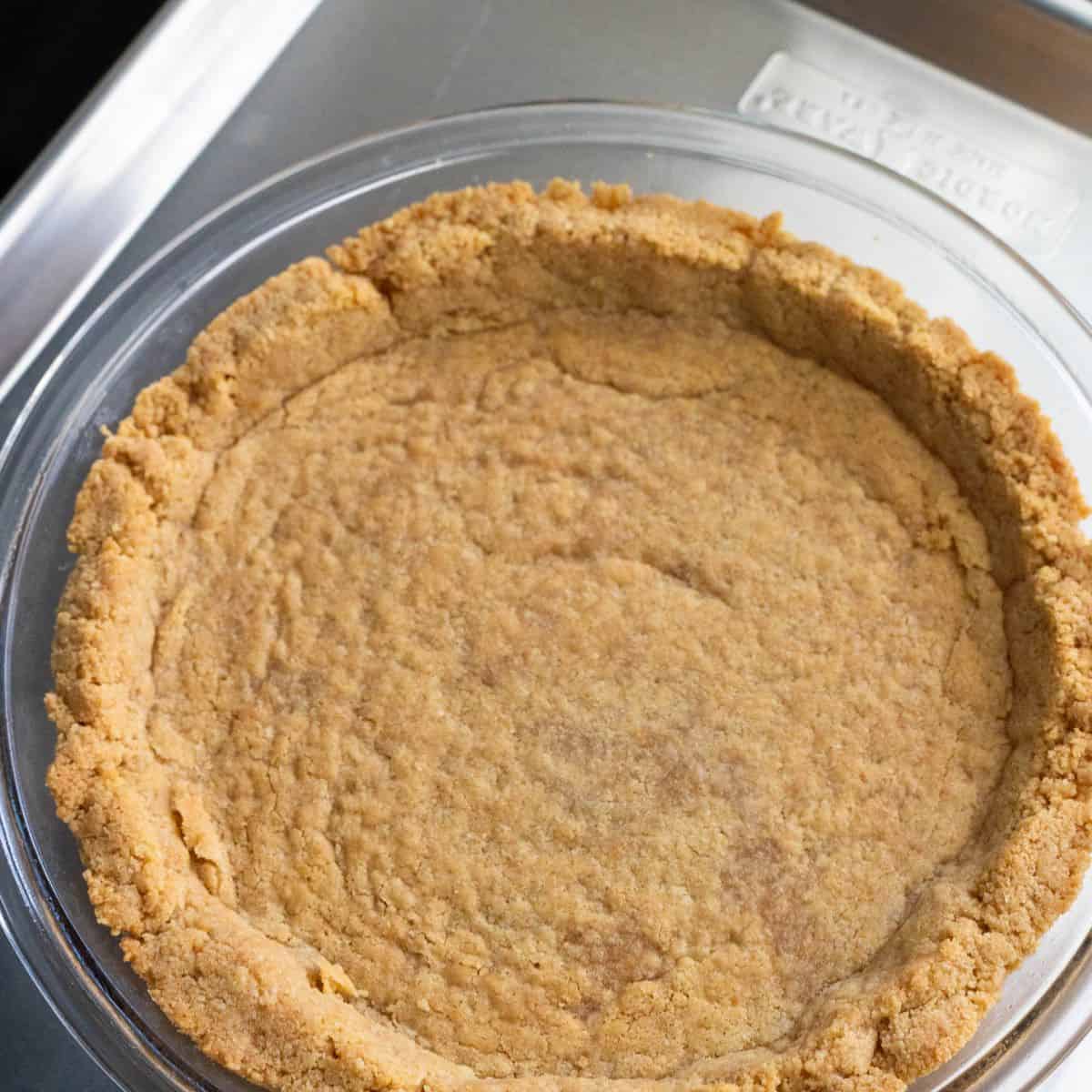 A baked saltine cracker crust rests on the stovetop and is ready for filling.