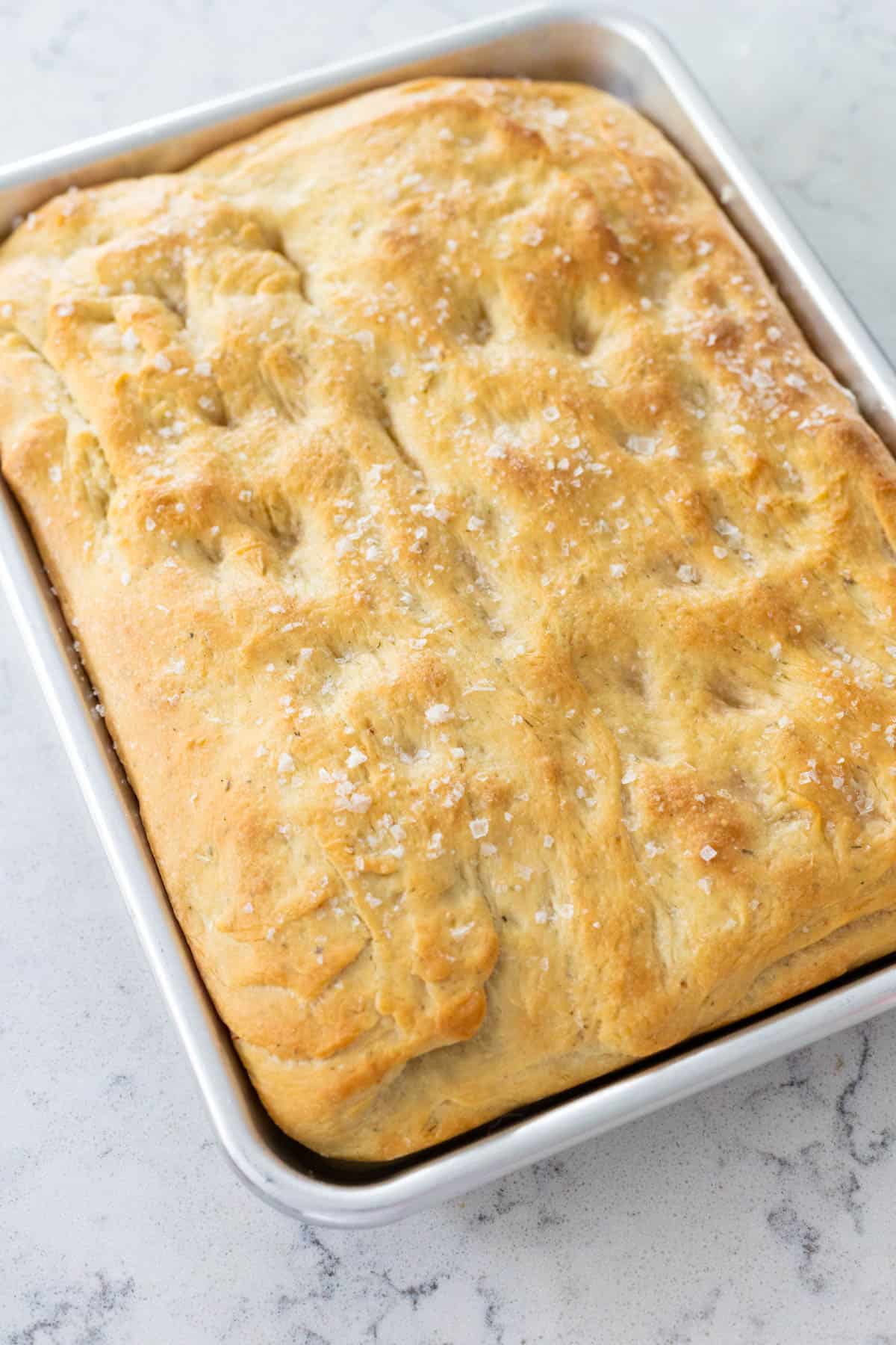 A pan of fresh focaccia sits on the kitchen counter.