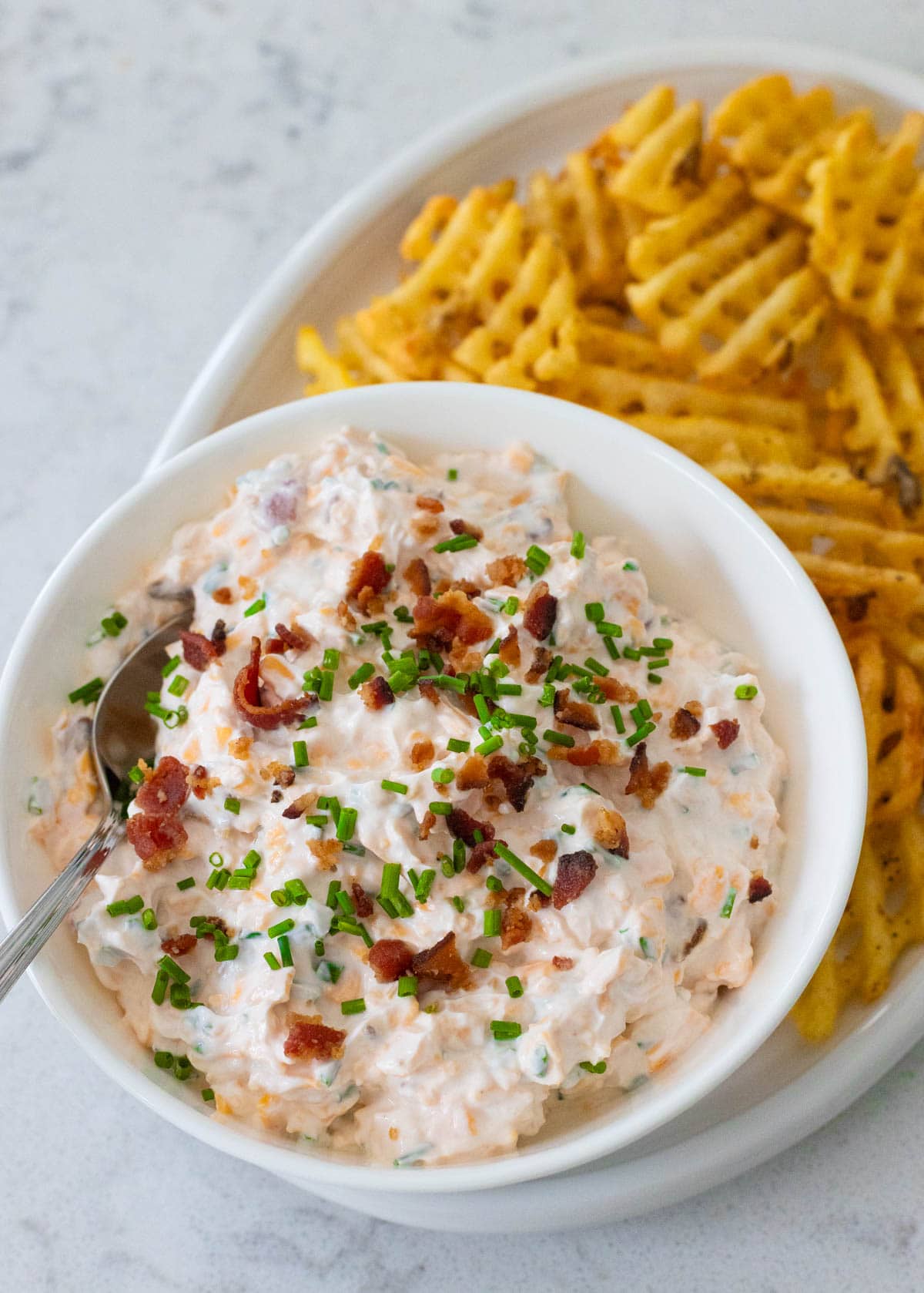 Creamy baked potato dip topped with bacon and chives, served with waffle fries.