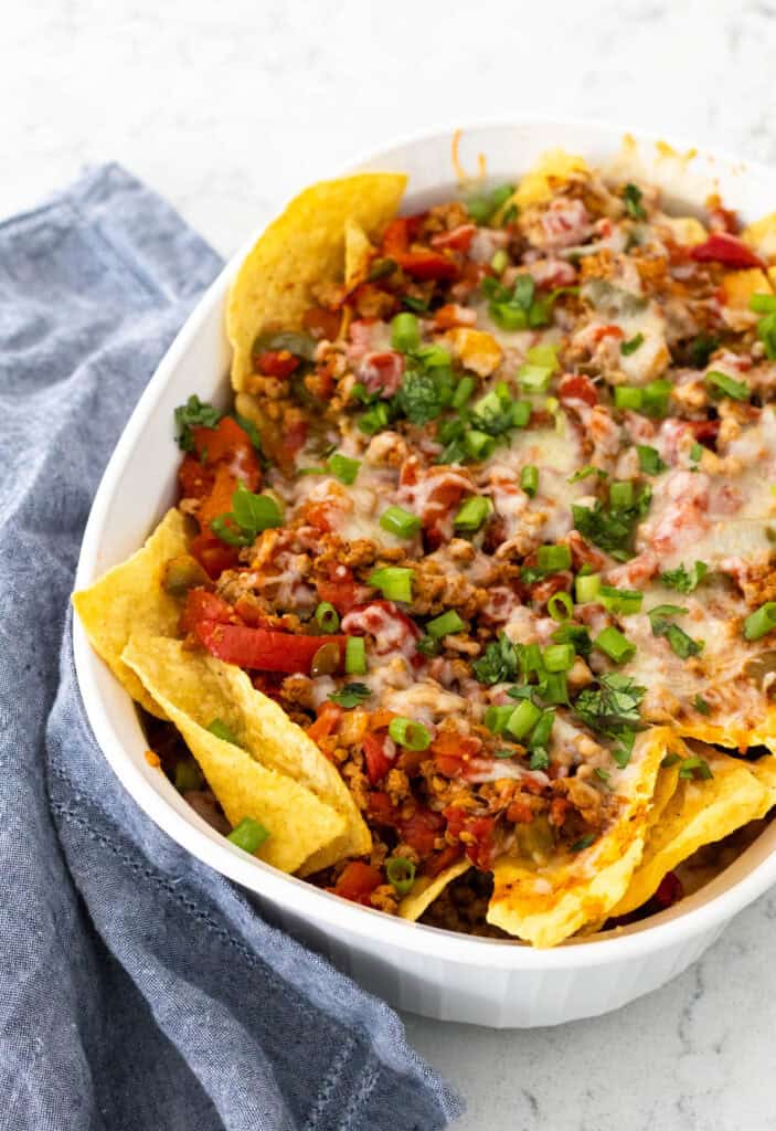 A casserole made with layers of nacho chips, turkey chorizo, vegetables, and melted cheese is cooling.
