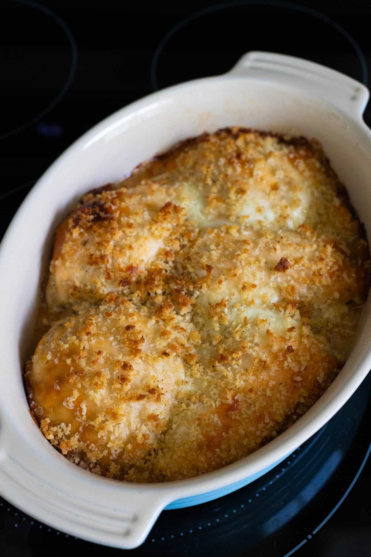 Golden, crispy baked chicken breasts in a white baking dish.