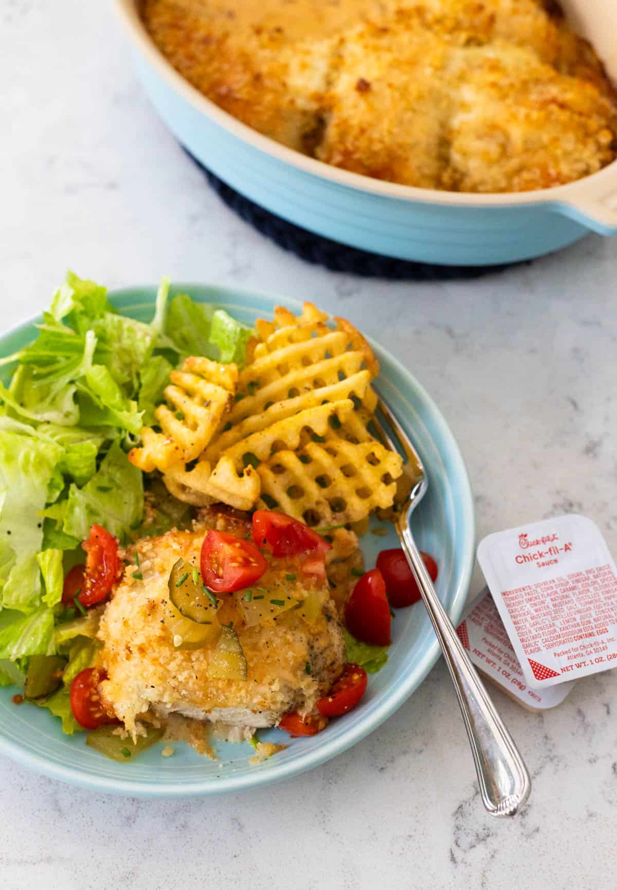 Plate of baked Chick-Fil-A style chicken with waffle fries, salad, and Chick-fil-A sauce.