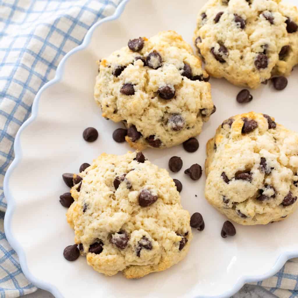 A white ruffled platter has 4 chocolate chip scones with chocolate chips scattered over the top.