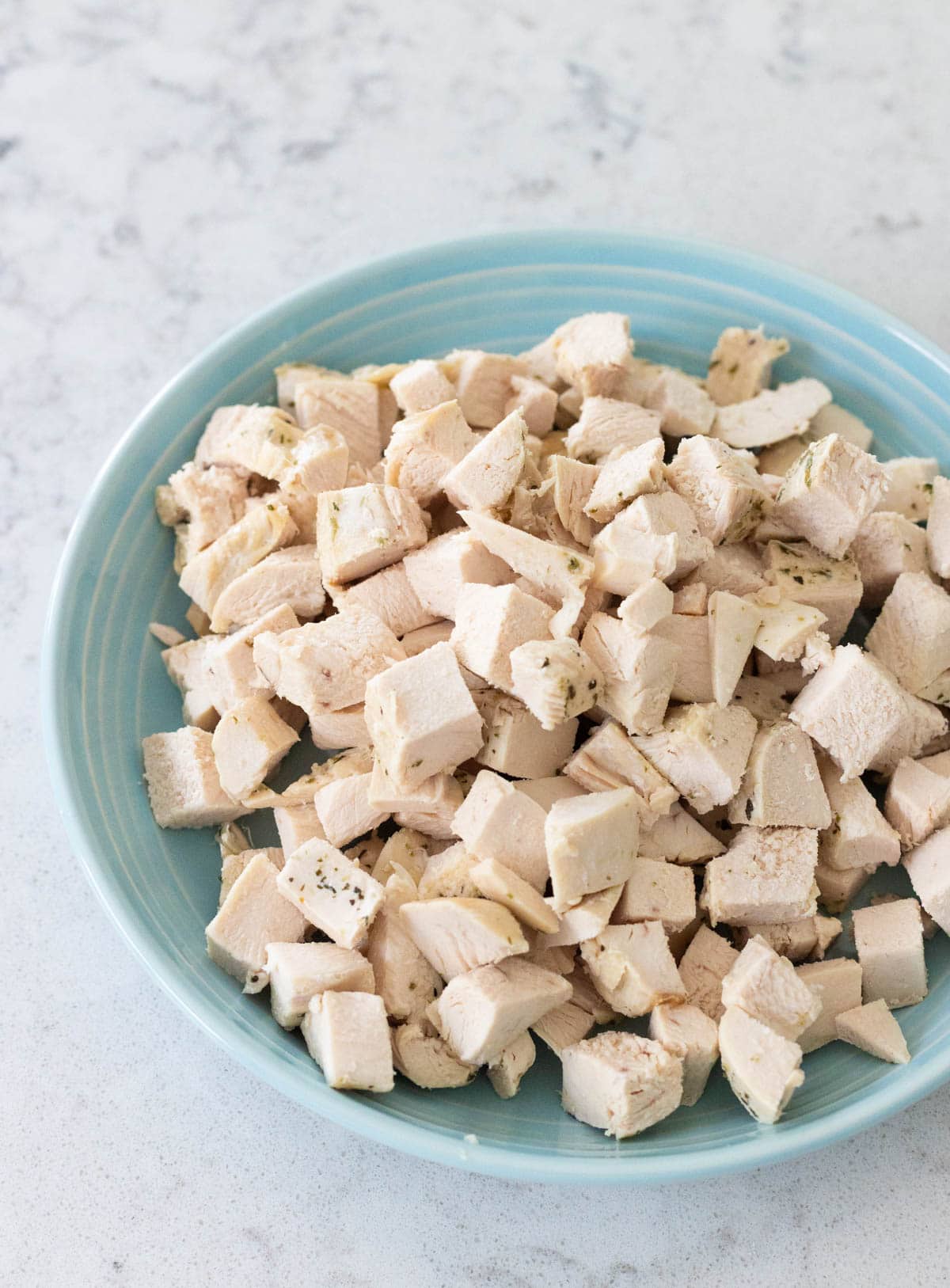 A close-up of a bowl filled with evenly cubed cooked chicken breast