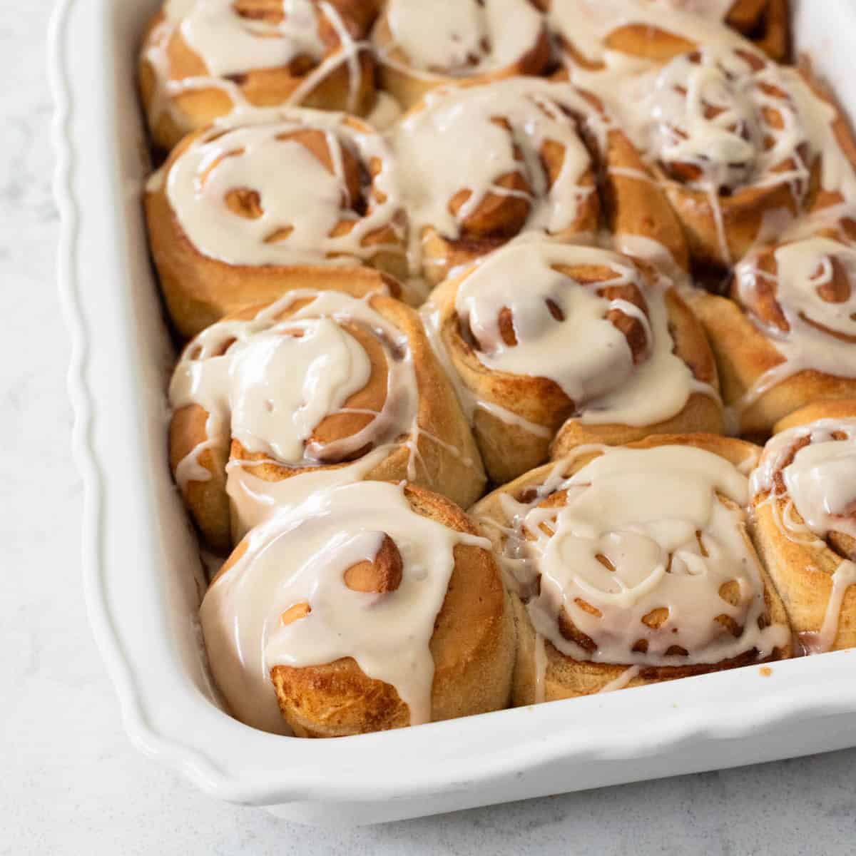 A baking pan of breakfast rolls has been drizzled with maple glaze.