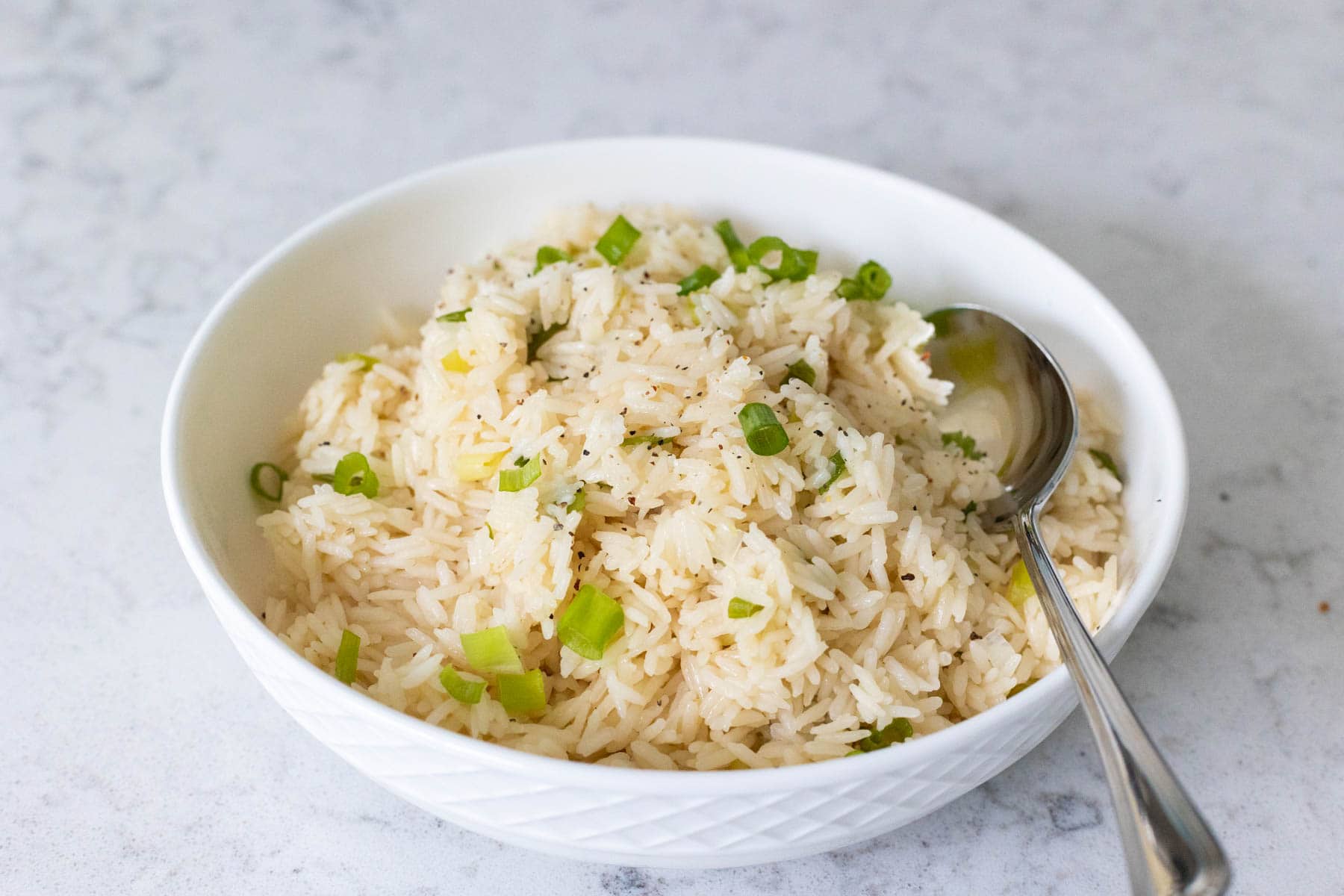 Scallion Rice in a Bowl and has a spoon on the side.
