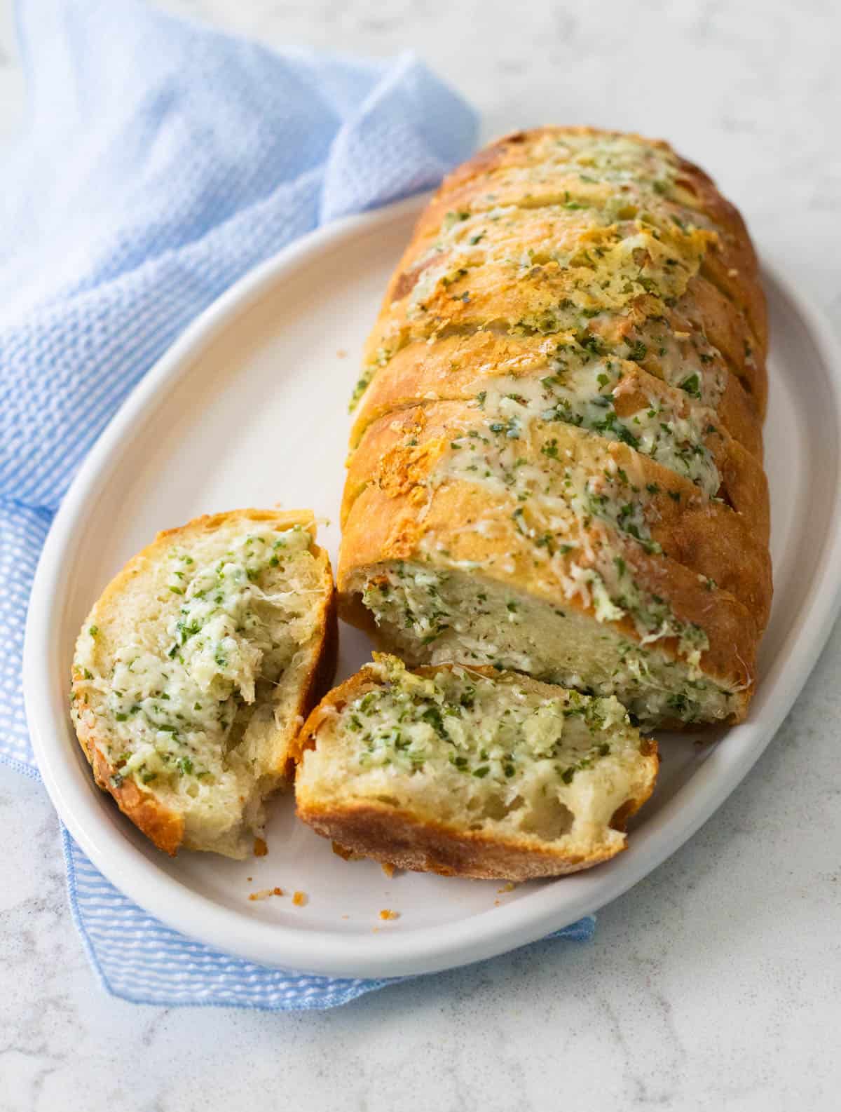 A piece of the bread is broken off, showing the soft, fluffy interior with a golden, cheesy crust.