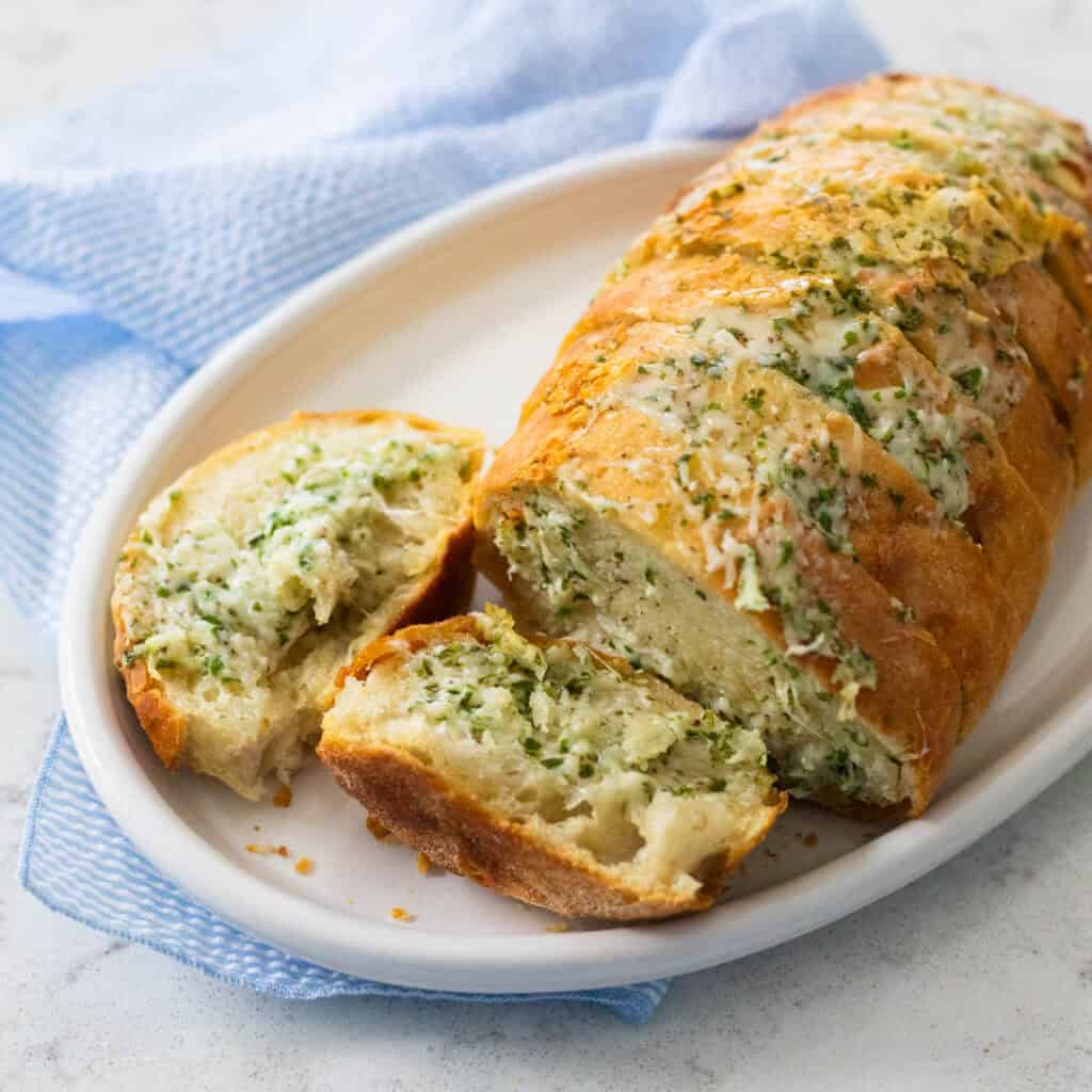 A loaf of french bread has been sliced and baked with garlic butter and shredded Swiss cheese between the layers.