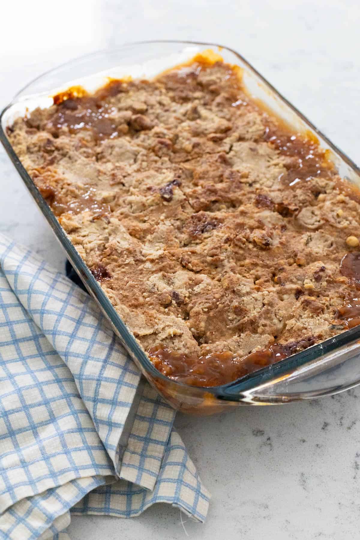 The finished apple snickerdoodle dump cake in a glass baking dish, with a golden crust and bubbling apple filling around the edges.