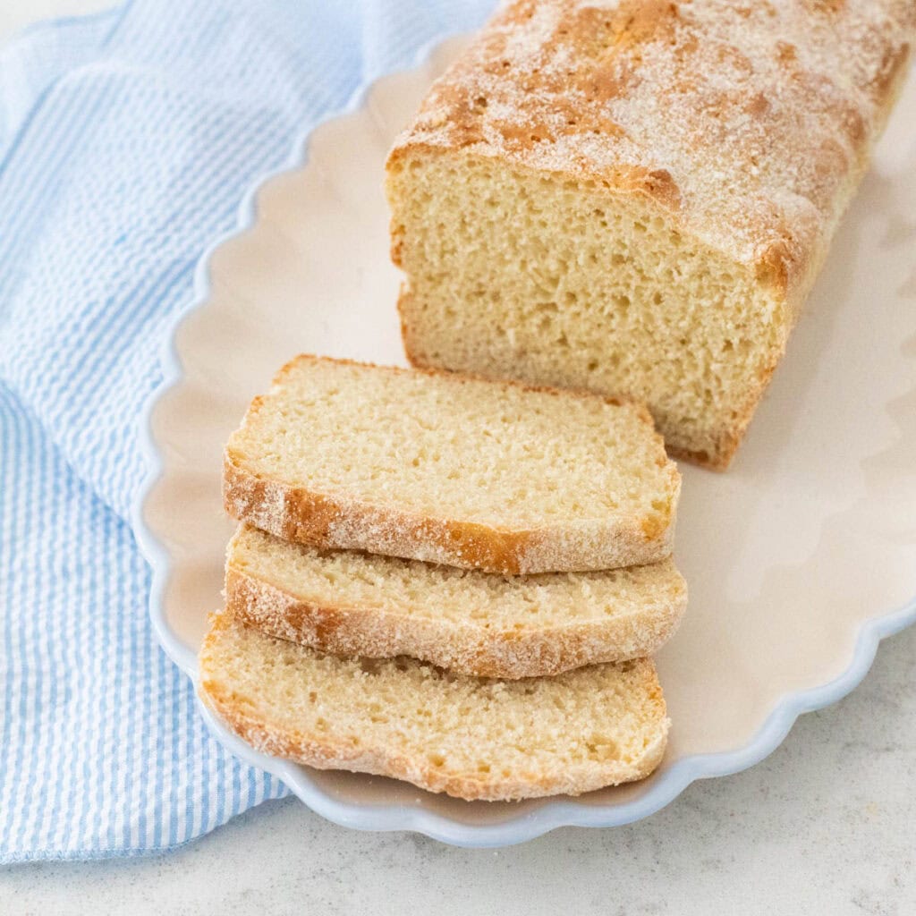 A loaf of English muffin bread has been sliced and served on a ruffled platter.