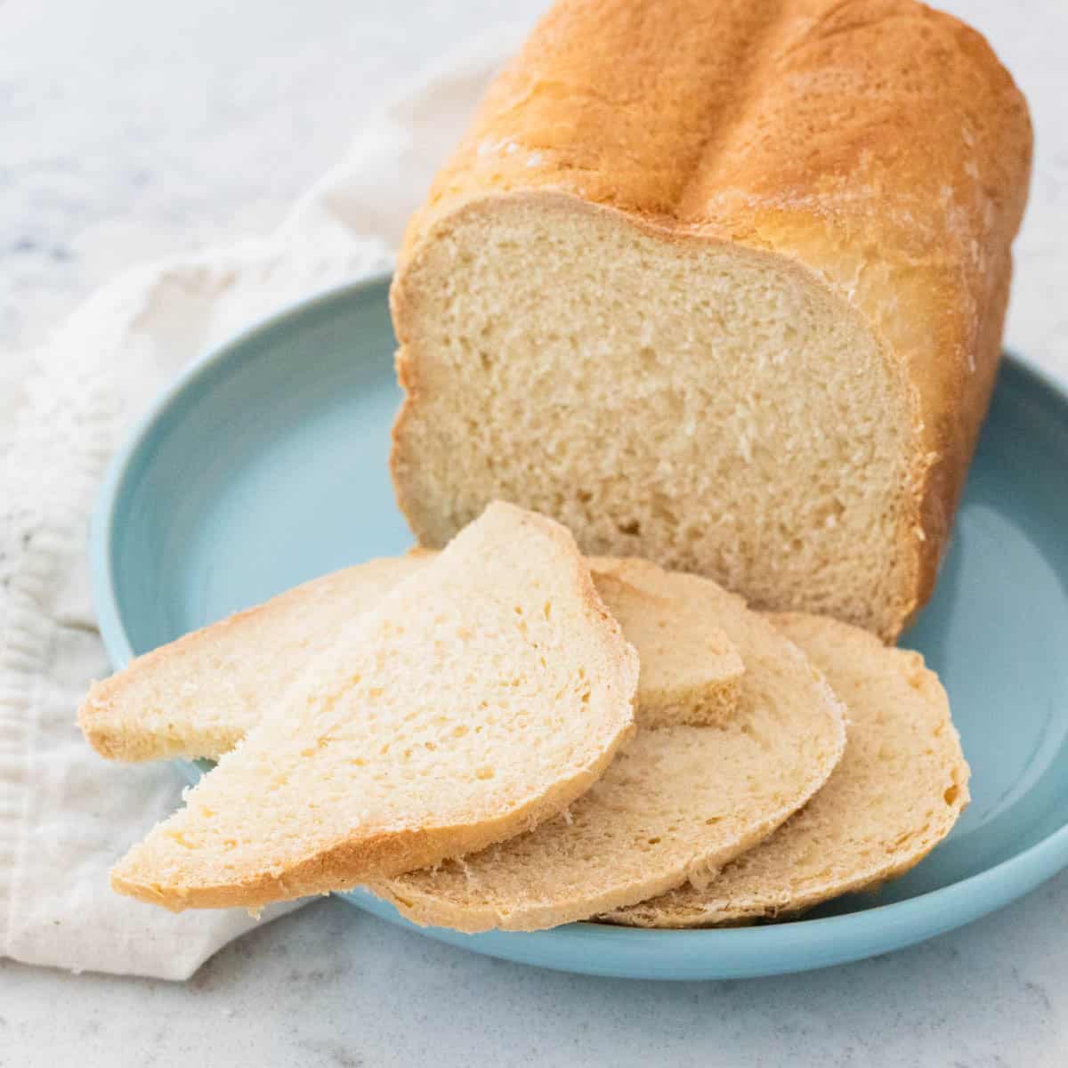 A loaf of bread machine French pear bread has been sliced and served on a blue plate.