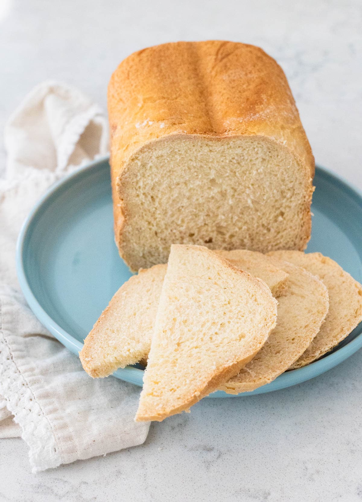 A loaf of bread machine French pear bread has been sliced and served on a blue plate.