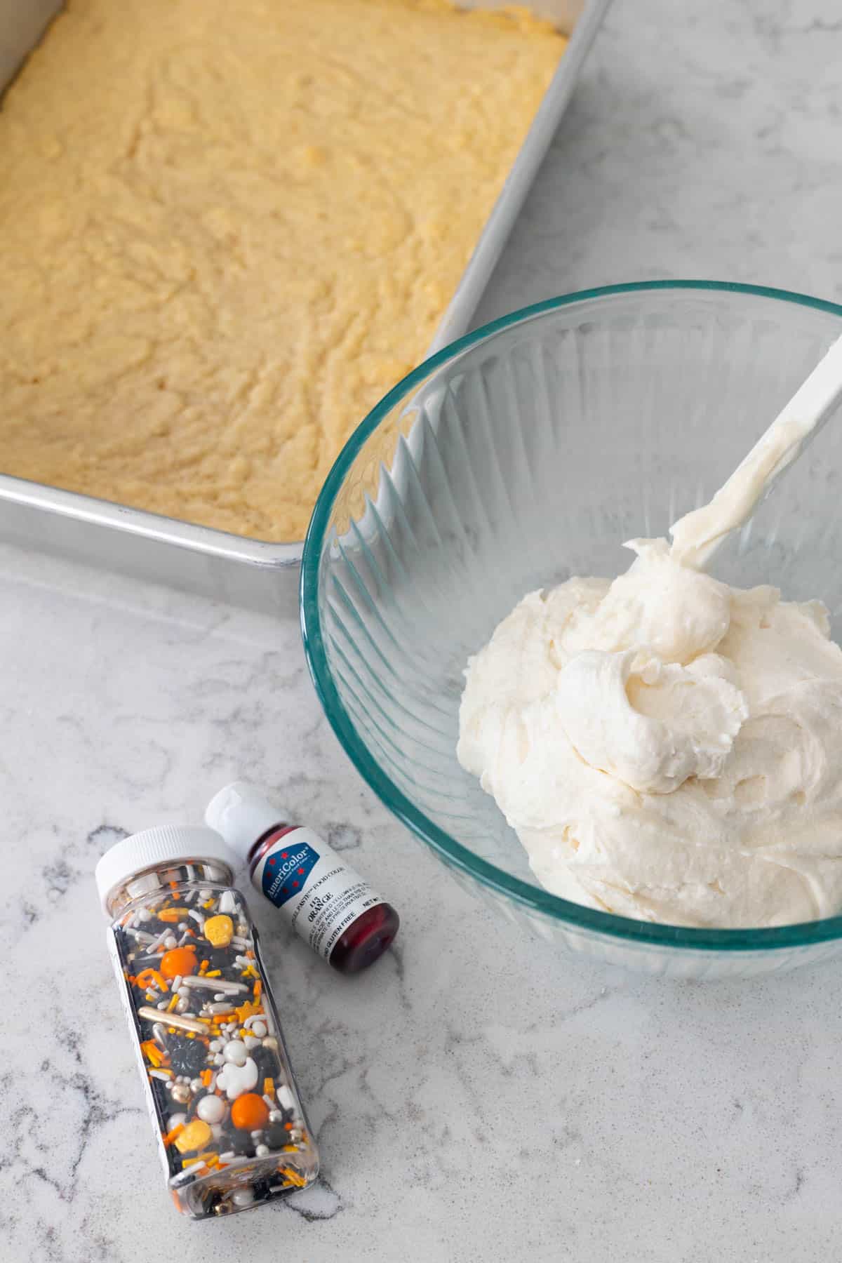 Les barres de cookies se trouvent à côté d'un bol de glaçage, de gel alimentaire et de paillettes.